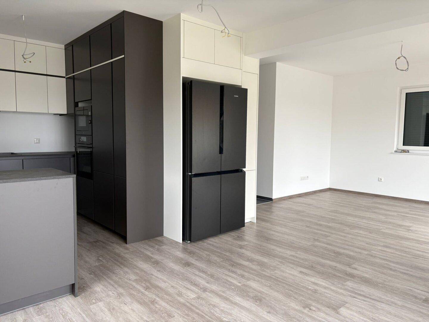 Offene Küche mit modernen Einbauschränken, integriertem Backofen und großem Kühlschrank.