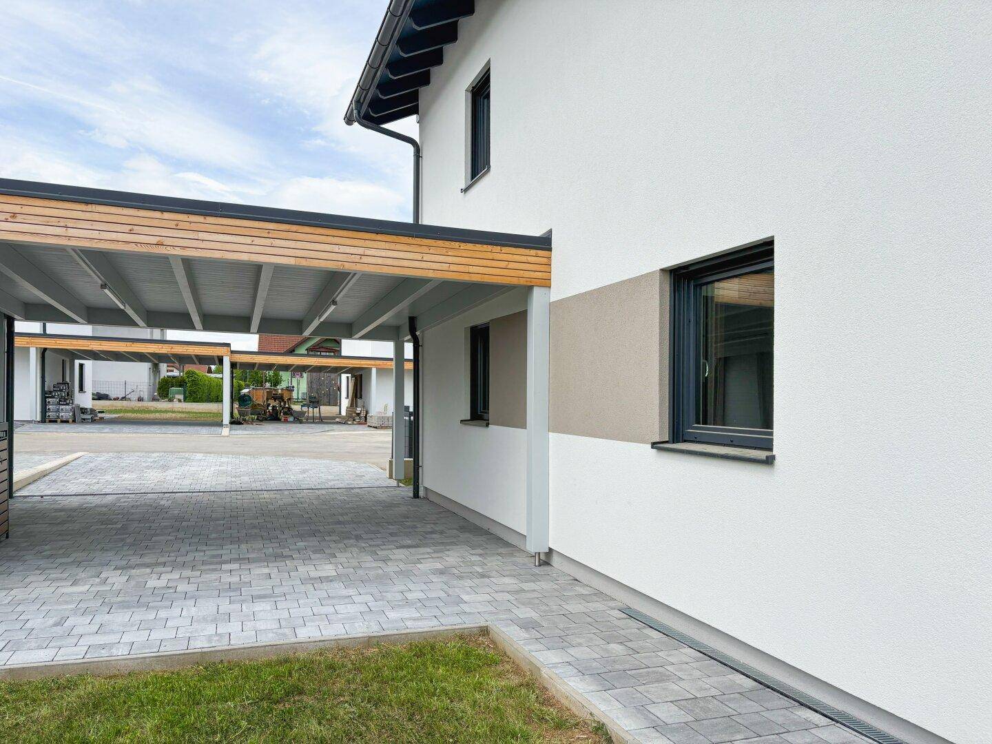 Seitenansicht des Hauses mit Carport und gepflasterter Einfahrt.