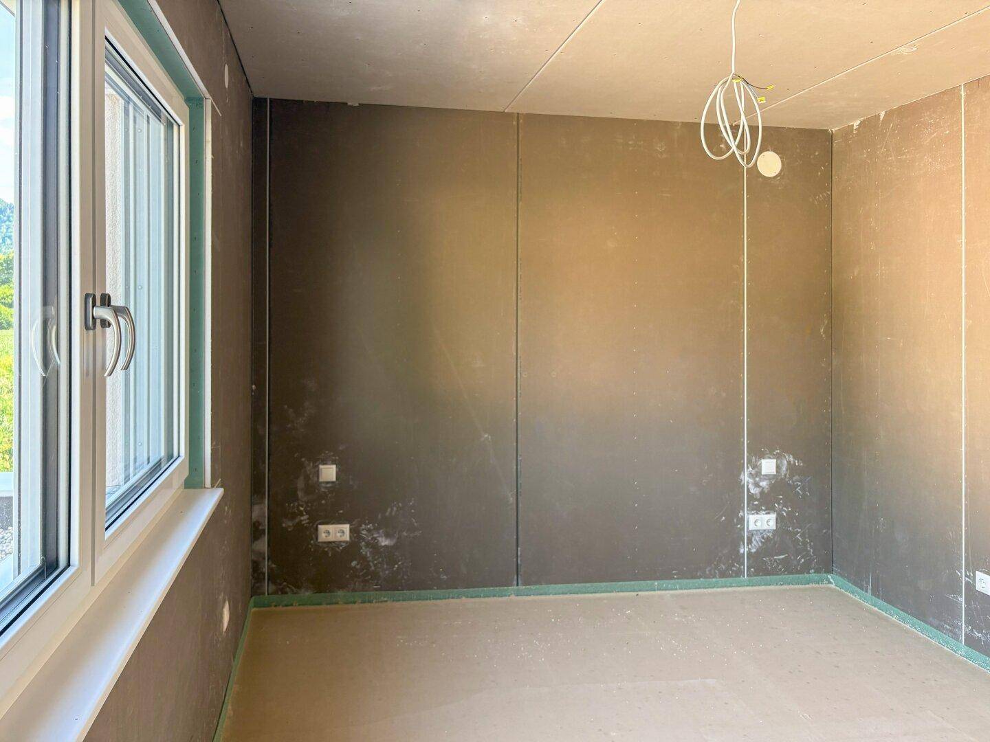 Unfertiges Zimmer mit einem Fenster, das viel natürliches Licht hereinlässt.