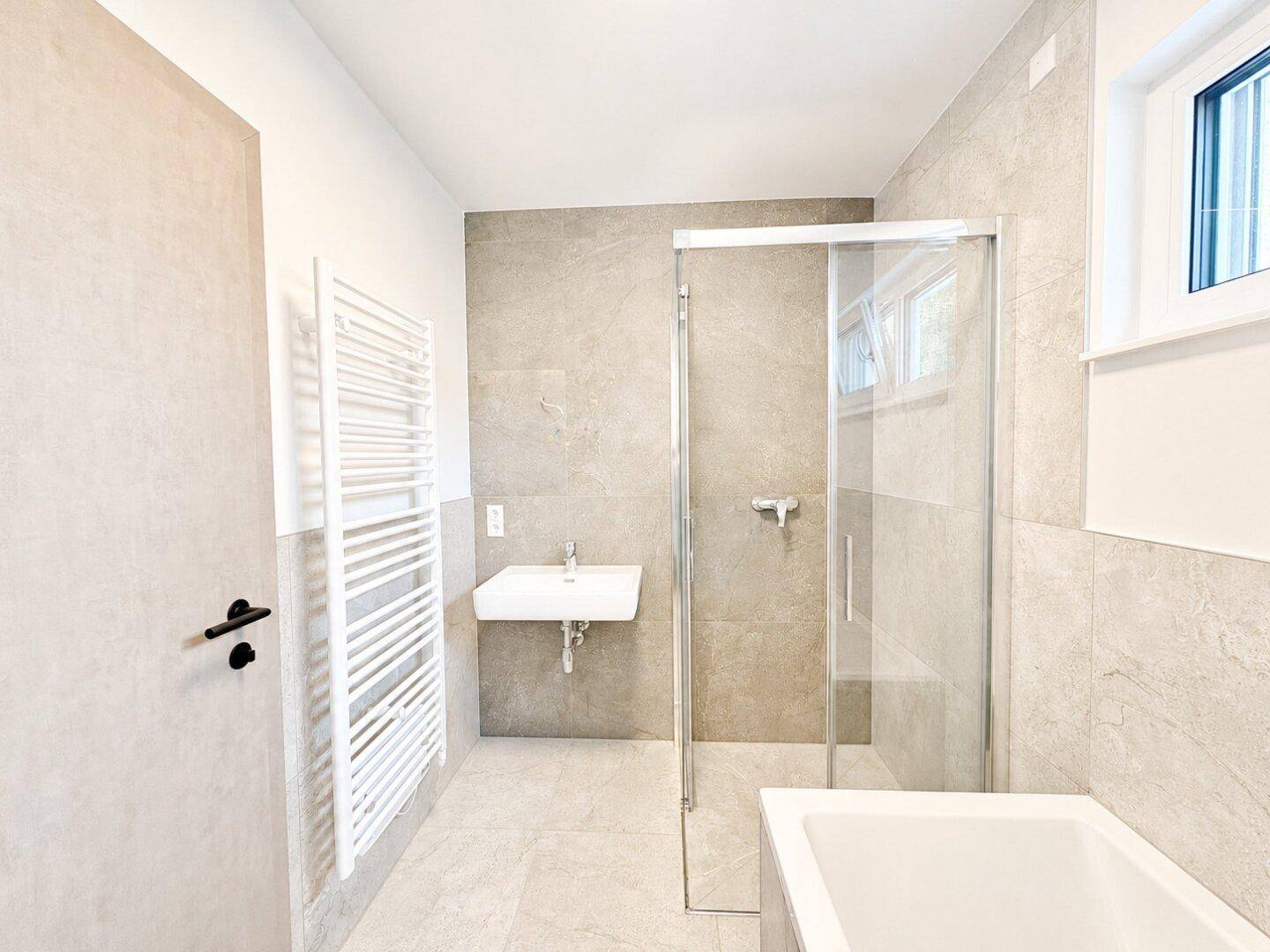 Modernes Badezimmer mit Dusche, Badewanne, Einzelwaschbecken und beheiztem Handtuchhalter.