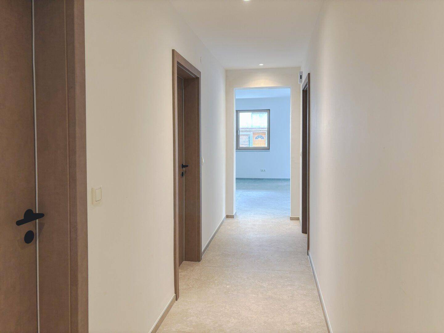 Heller Flur mit modernen Holztüren und Einbaustrahlern in der Decke.