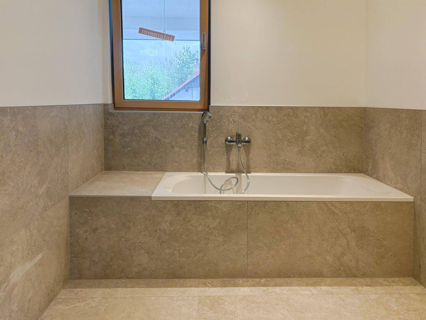 Modernes Badezimmer mit eingebauter Badewanne und Fenster für natürliches Tageslicht.