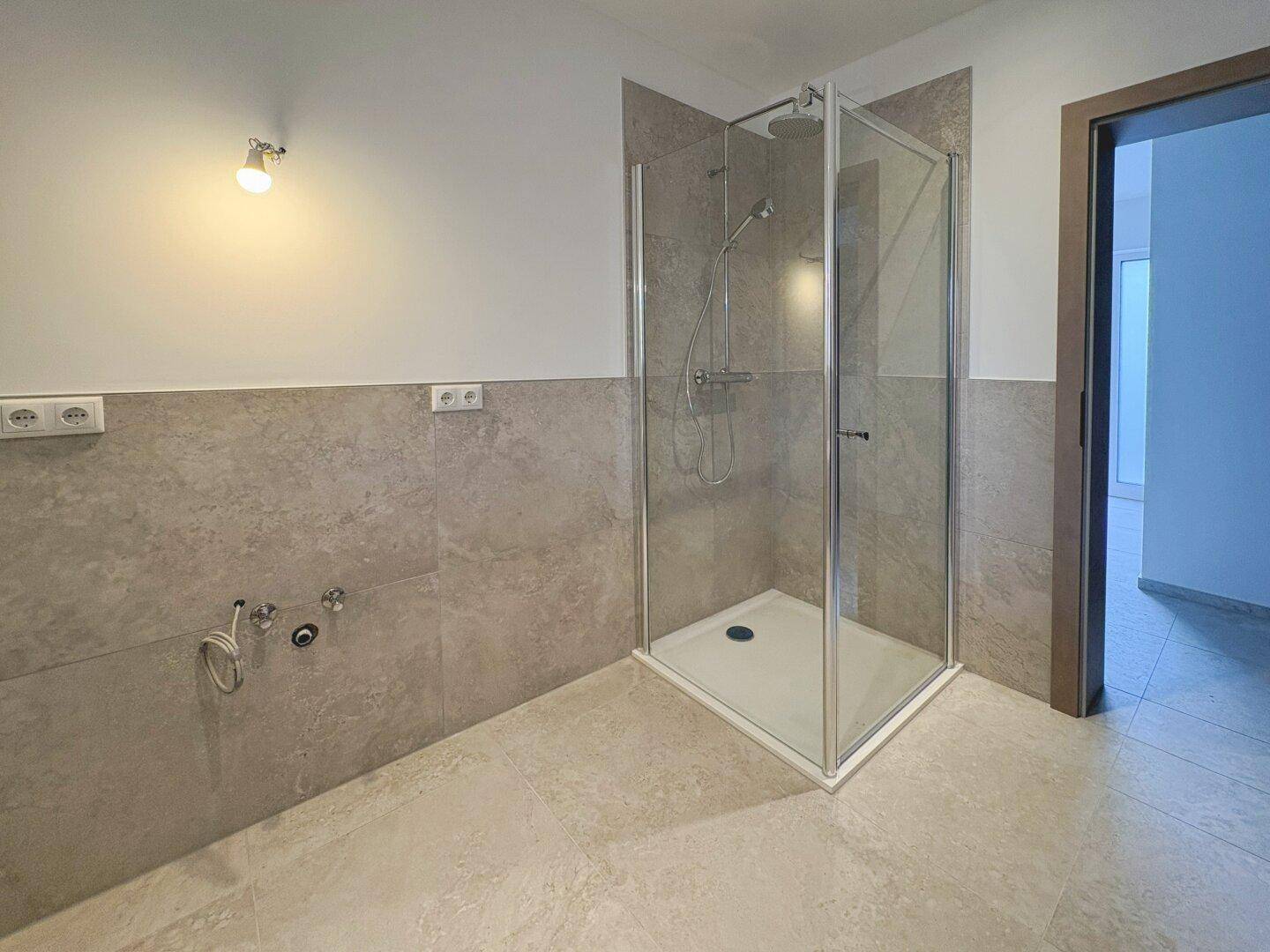 Helles Badezimmer mit Duschkabine und modernen Fliesen an Wänden und Boden, neuwertig und funktional.