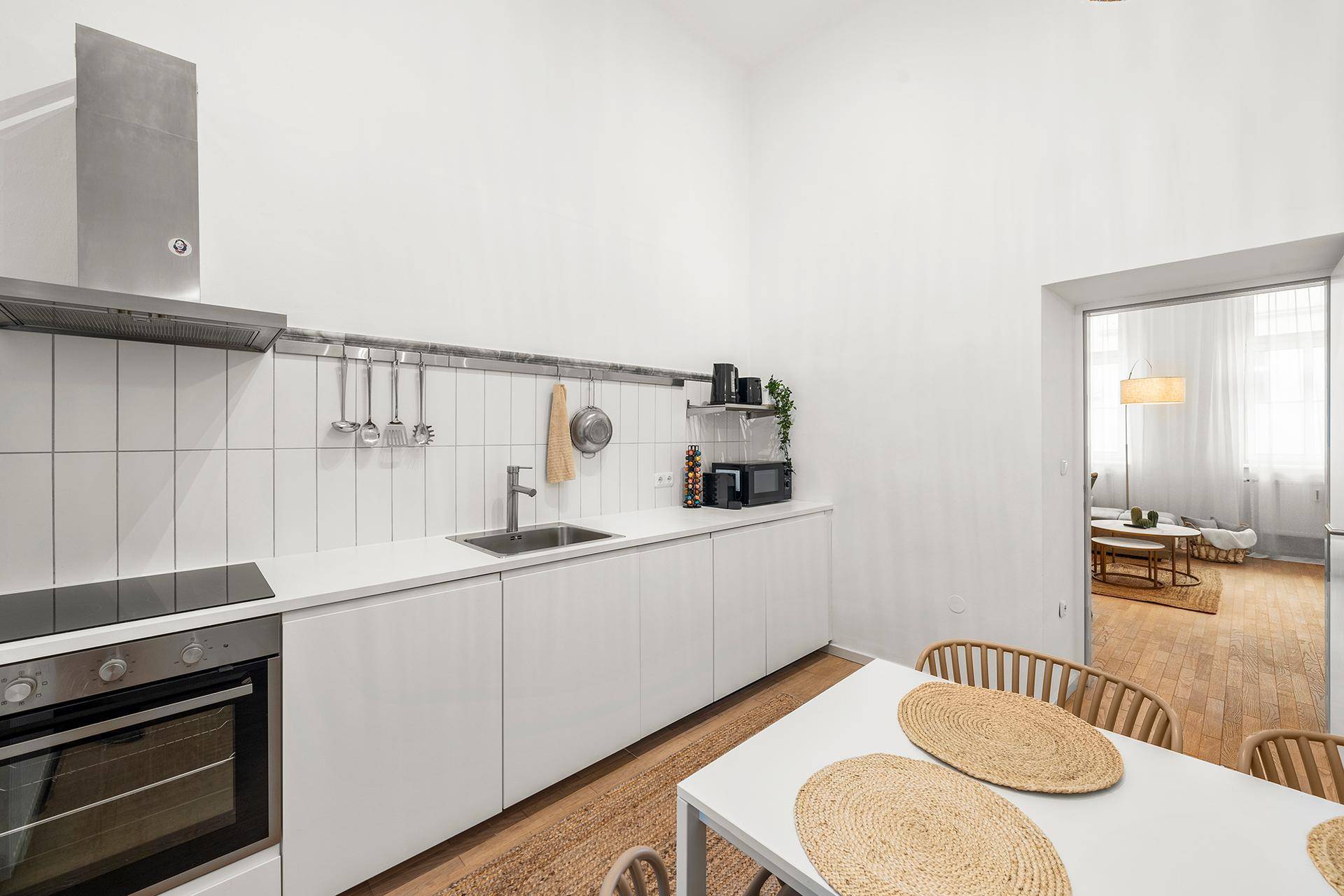 Moderne Einbauküche mit weißen Fronten, Essbereich und Blick in den offenen Wohnbereich.