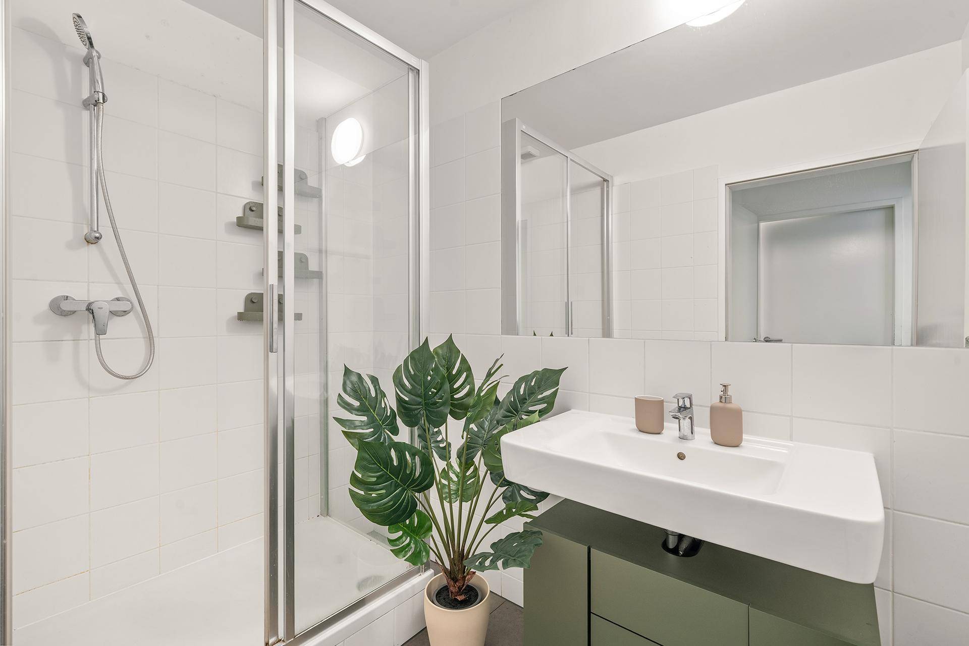 Modernes Badezimmer mit Dusche, Waschbecken und großem Spiegel.