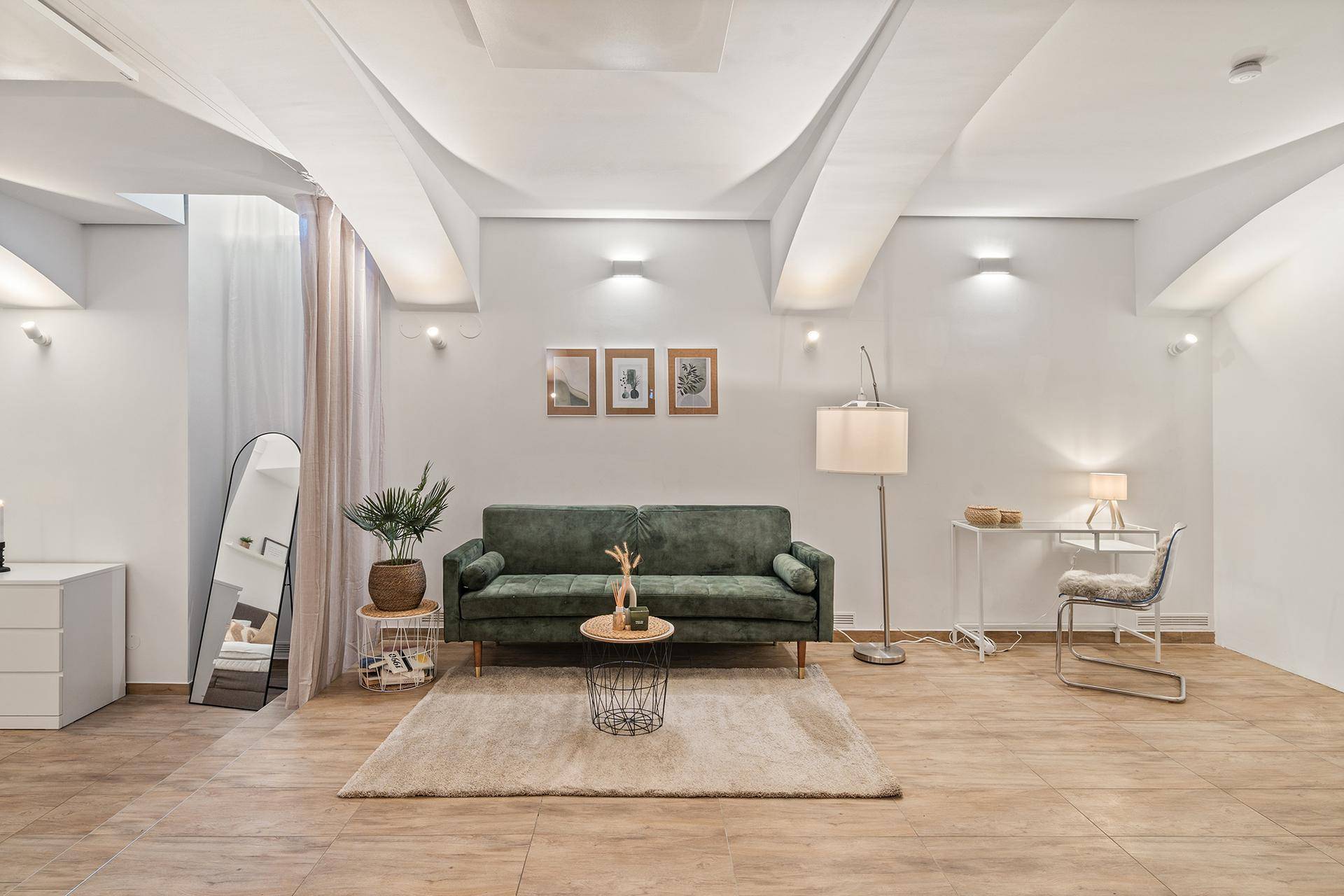 Geräumiges Wohnzimmer mit grünem Sofa, Teppich und stilvoller Dekoration.