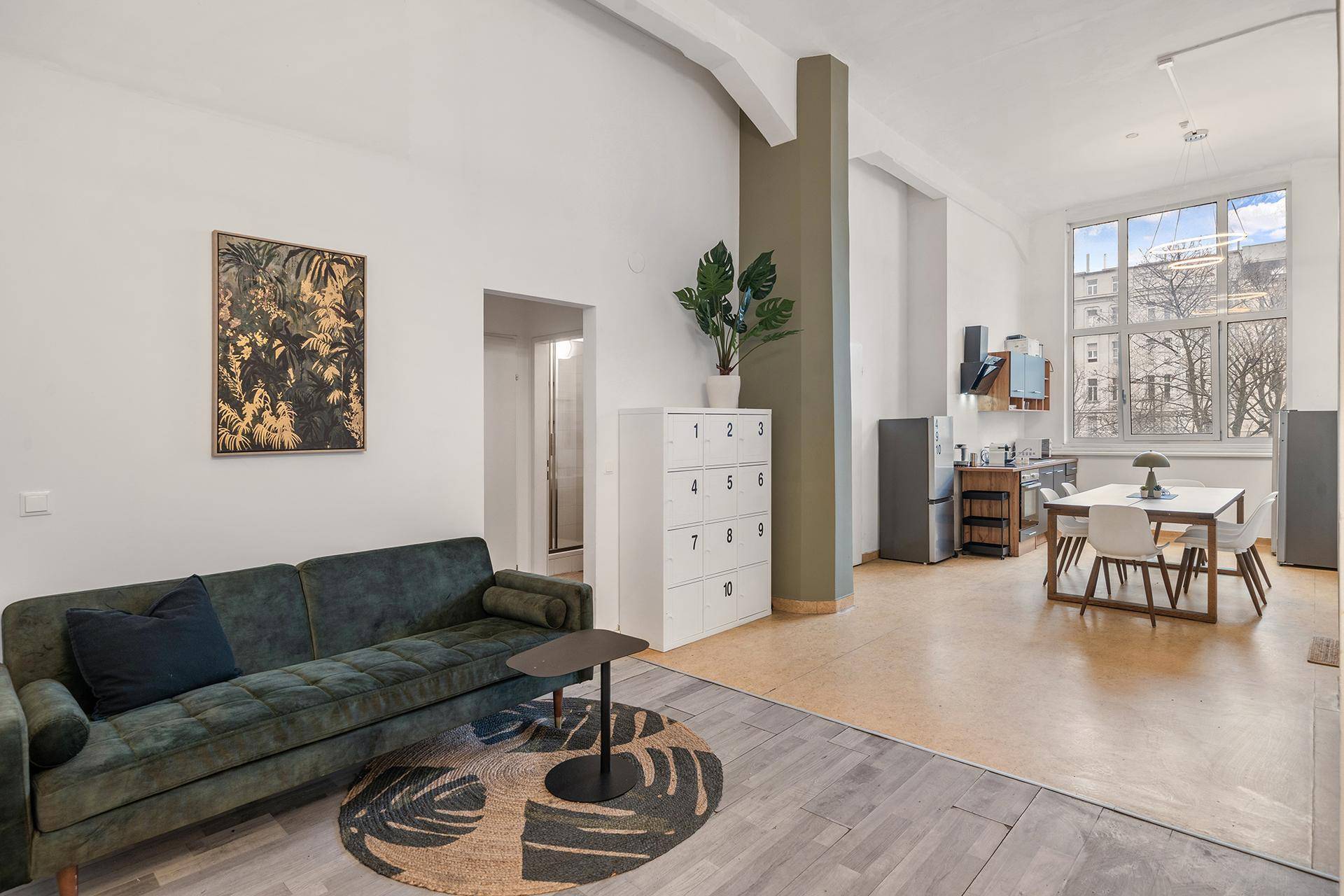 Geräumiger Wohnbereich mit Sofa, Teppich und offener Verbindung zur Küche.
