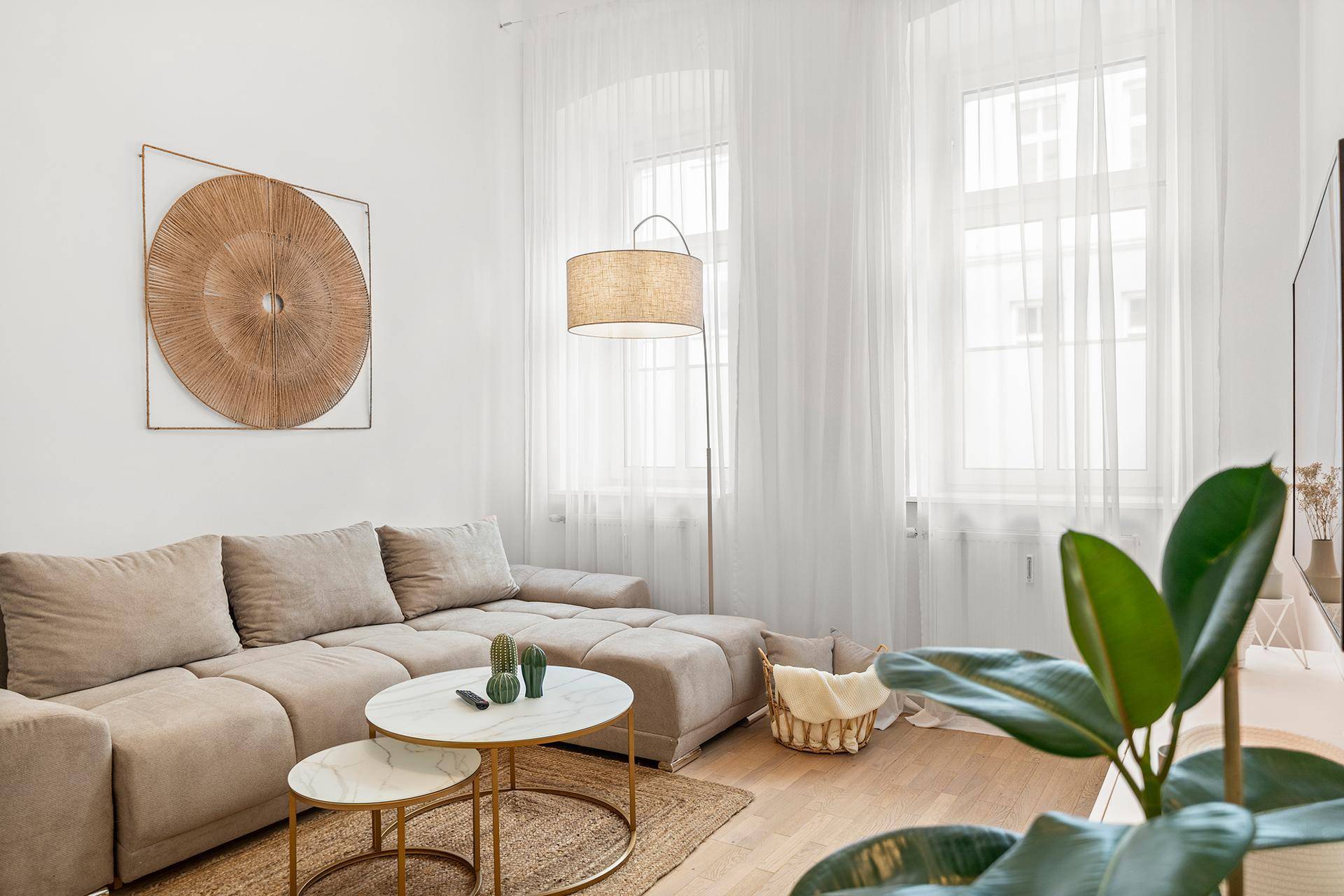 Gemütliches Wohnzimmer mit großem Sofa, Holzboden und viel Tageslicht durch die Fenster.