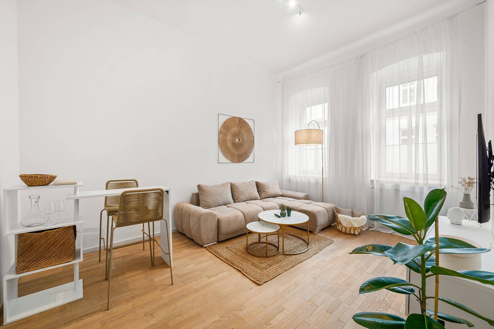 Offener Wohn- und Essbereich mit beigem Sofa, Bartisch und Holzboden in modernem Ambiente.