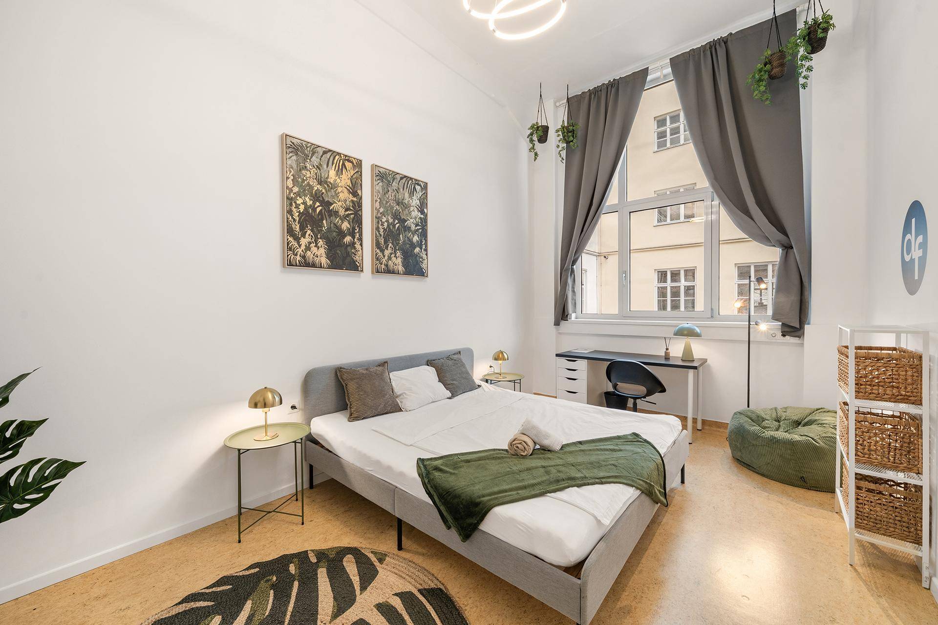 Helles Schlafzimmer mit einem Doppelbett, Schreibtisch und großen Fenstern, modern eingerichtet.