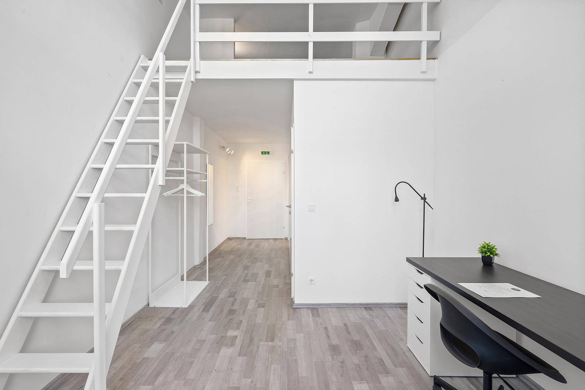 Geräumiges Zimmer mit Hochbett-Konstruktion, Schreibtisch und Holztreppe.