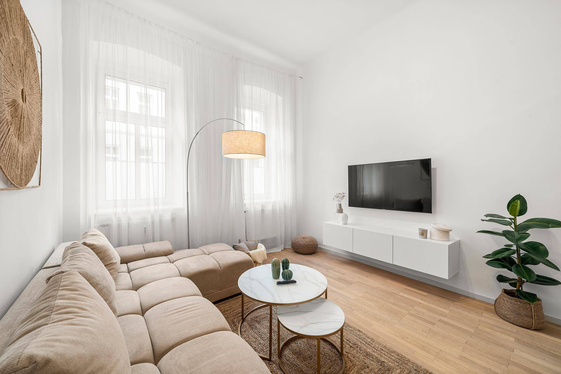 Geräumiges Wohnzimmer mit großem Ecksofa, Fernseher und Holzboden in hellem Ambiente.