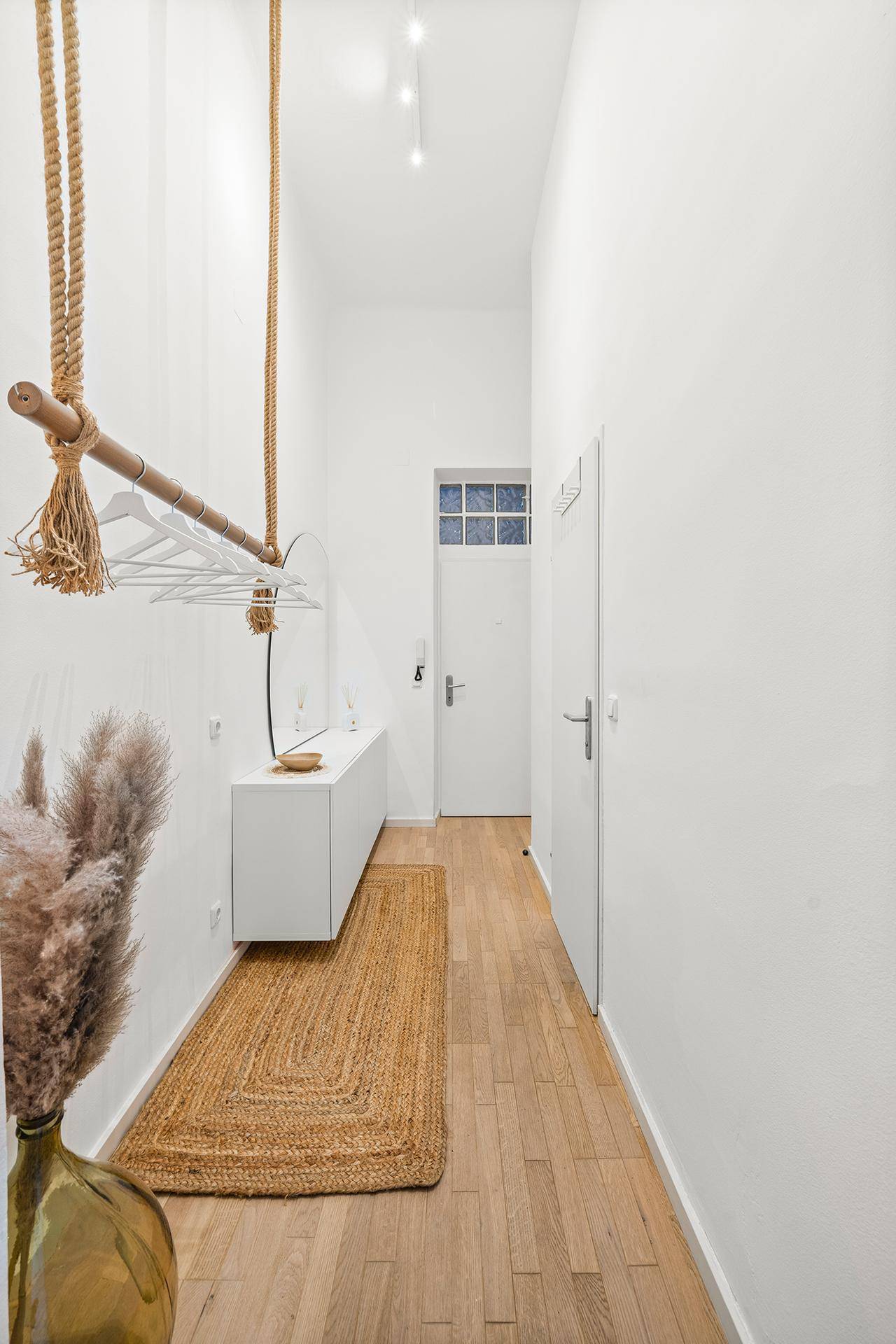 Langer, heller Flur mit Holzboden und einer modernen Hängegarderobe in minimalistischem Stil.
