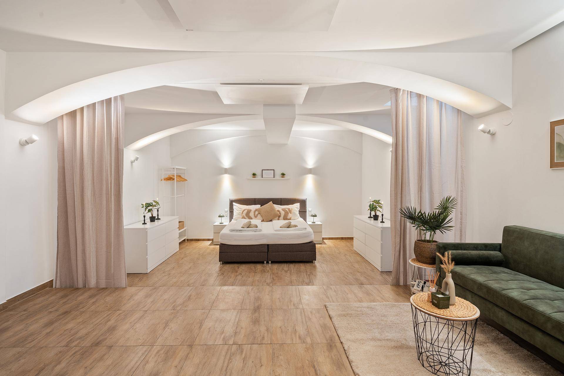 Großes Schlafzimmer mit Doppelbett, Nachttischen und indirekter Beleuchtung.