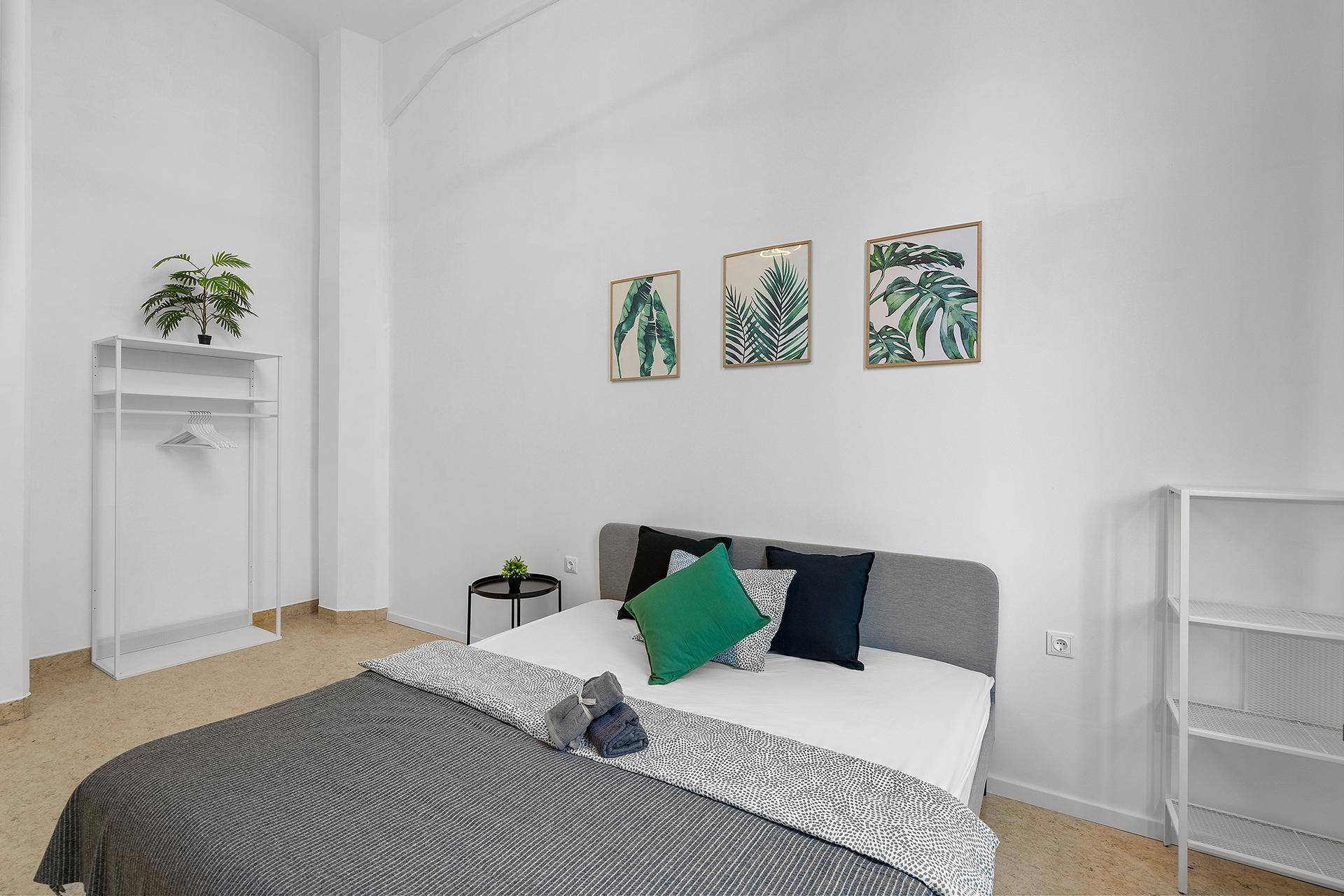 Schlafzimmer mit Doppelbett, Nachttisch und minimalistischer Dekoration.