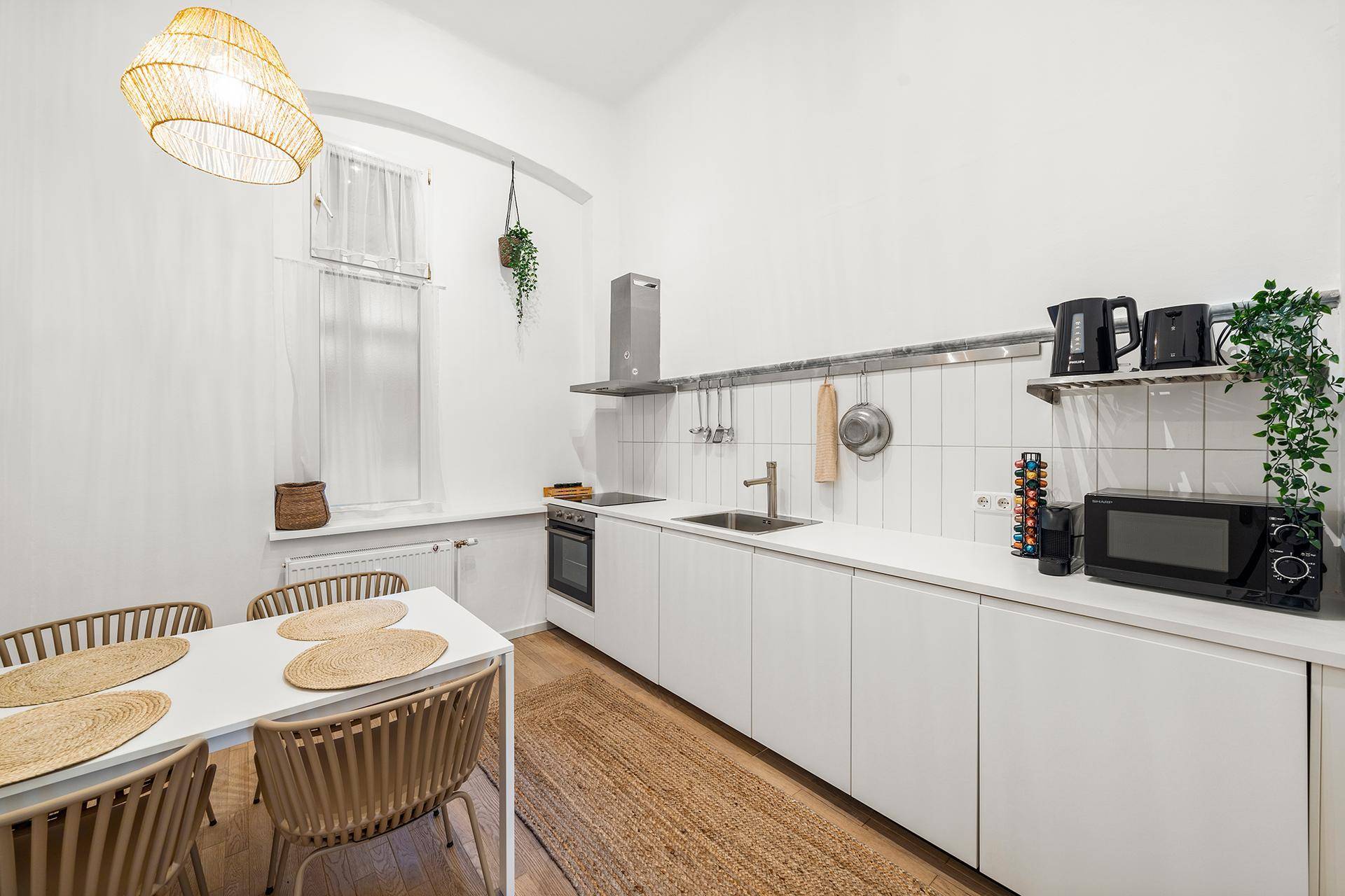 Moderne Küche mit weißen Schränken, Essbereich und integrierten Geräten in hellem Design.