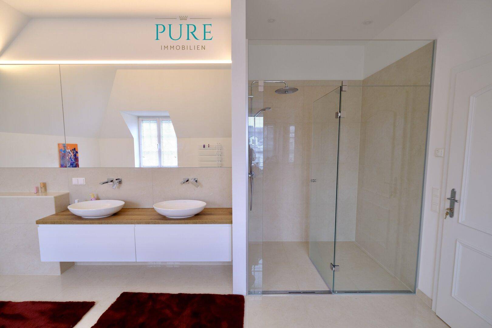 Geräumiges Badezimmer mit Doppelwaschbecken, großer Spiegelfront und begehbarer Dusche.