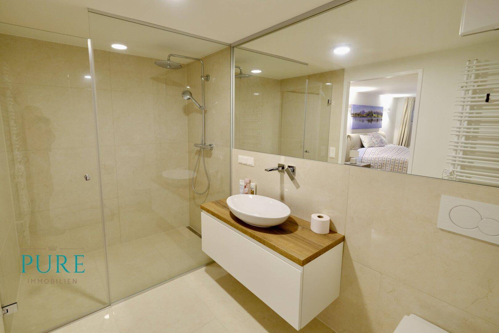 Modernes Badezimmer mit begehbarer Dusche, Waschbecken und großem Spiegel.