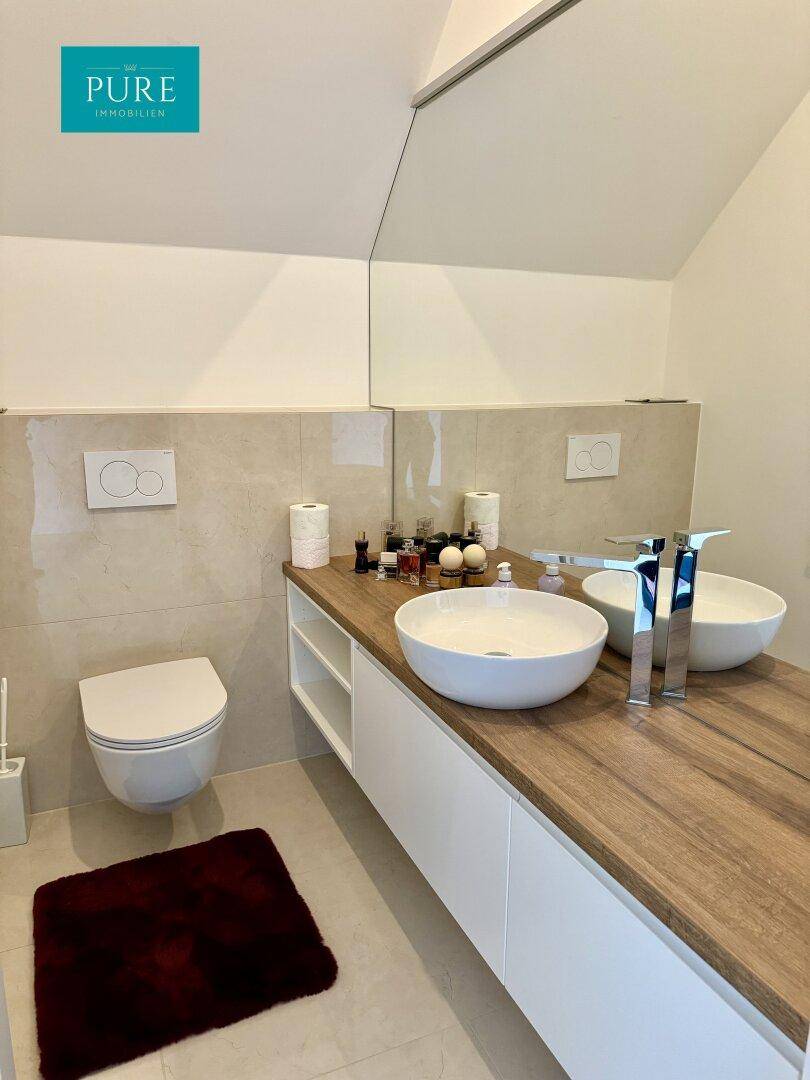 Modernes Badezimmer mit Doppelwaschbecken, Holzwaschtisch und Wand-WC im Dachgeschoss.