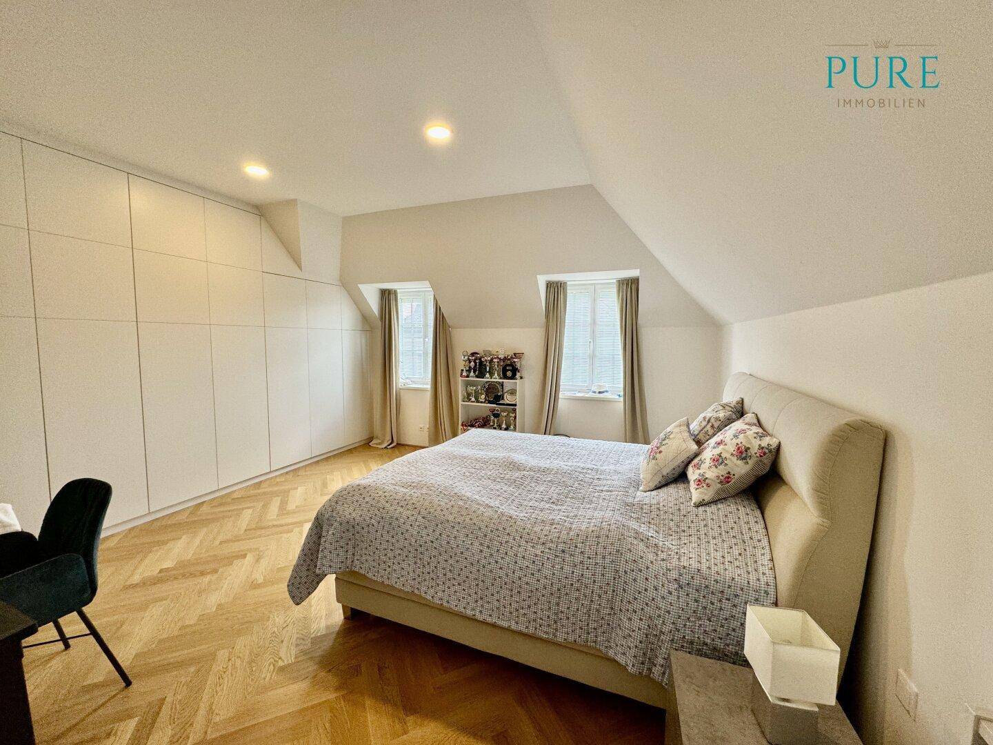 Geräumiges Schlafzimmer mit Einbauschränken, Parkettboden und Dachfenstern.
