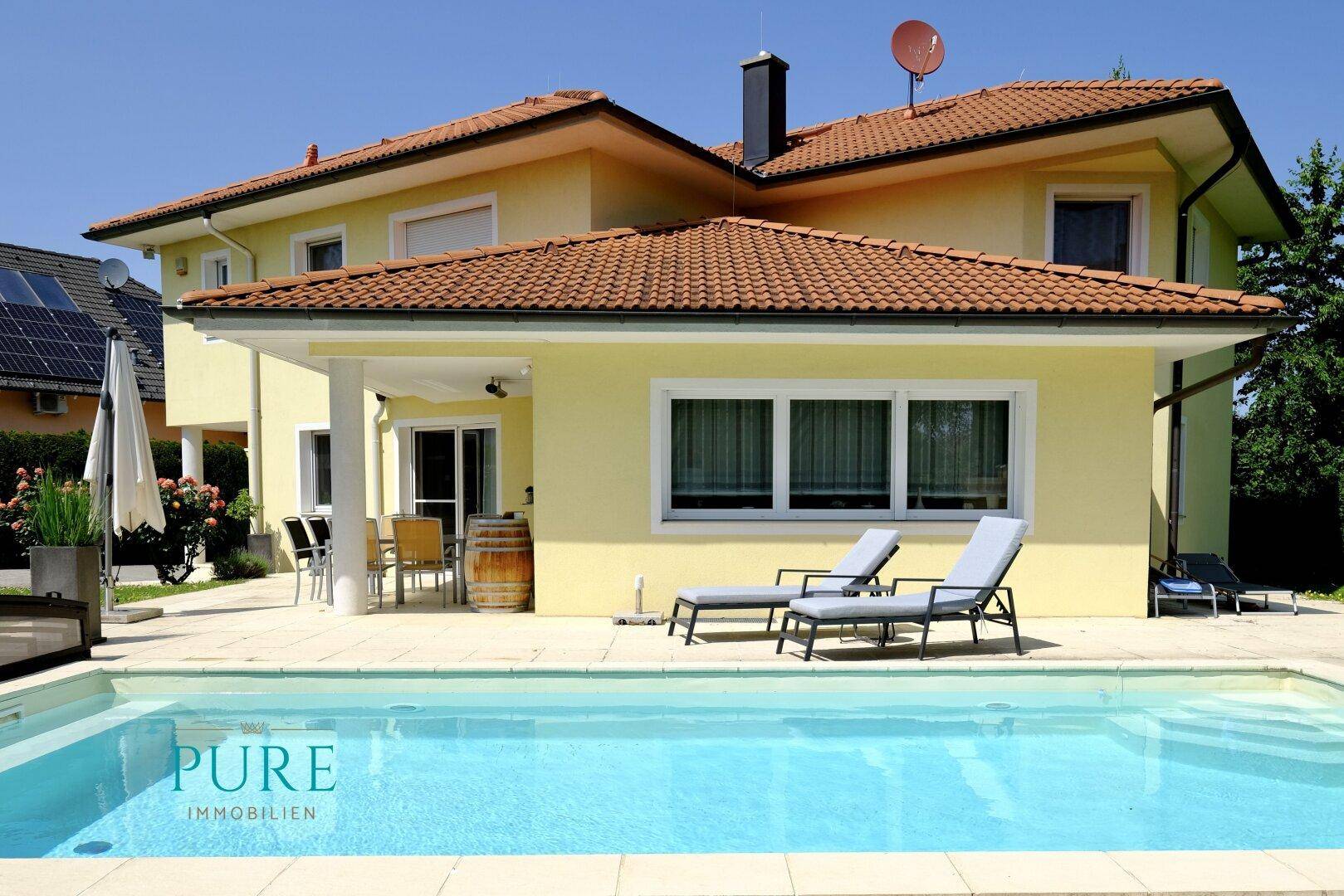 Attraktives Einfamilienhaus mit großem Pool, Liegestühlen und gepflegtem Gartenbereich.
