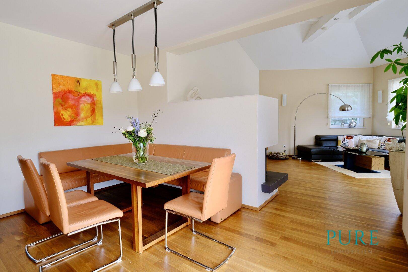 Helles Wohn- und Esszimmer mit Holzboden, moderner Einrichtung und Kunst an der Wand.