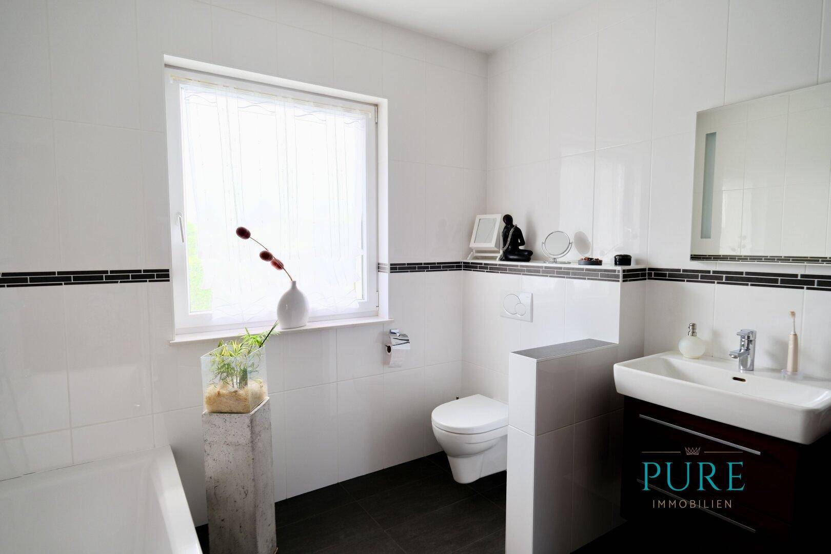 Modernes Gäste-WC mit wandhängender Toilette, Waschbecken und Fenster.