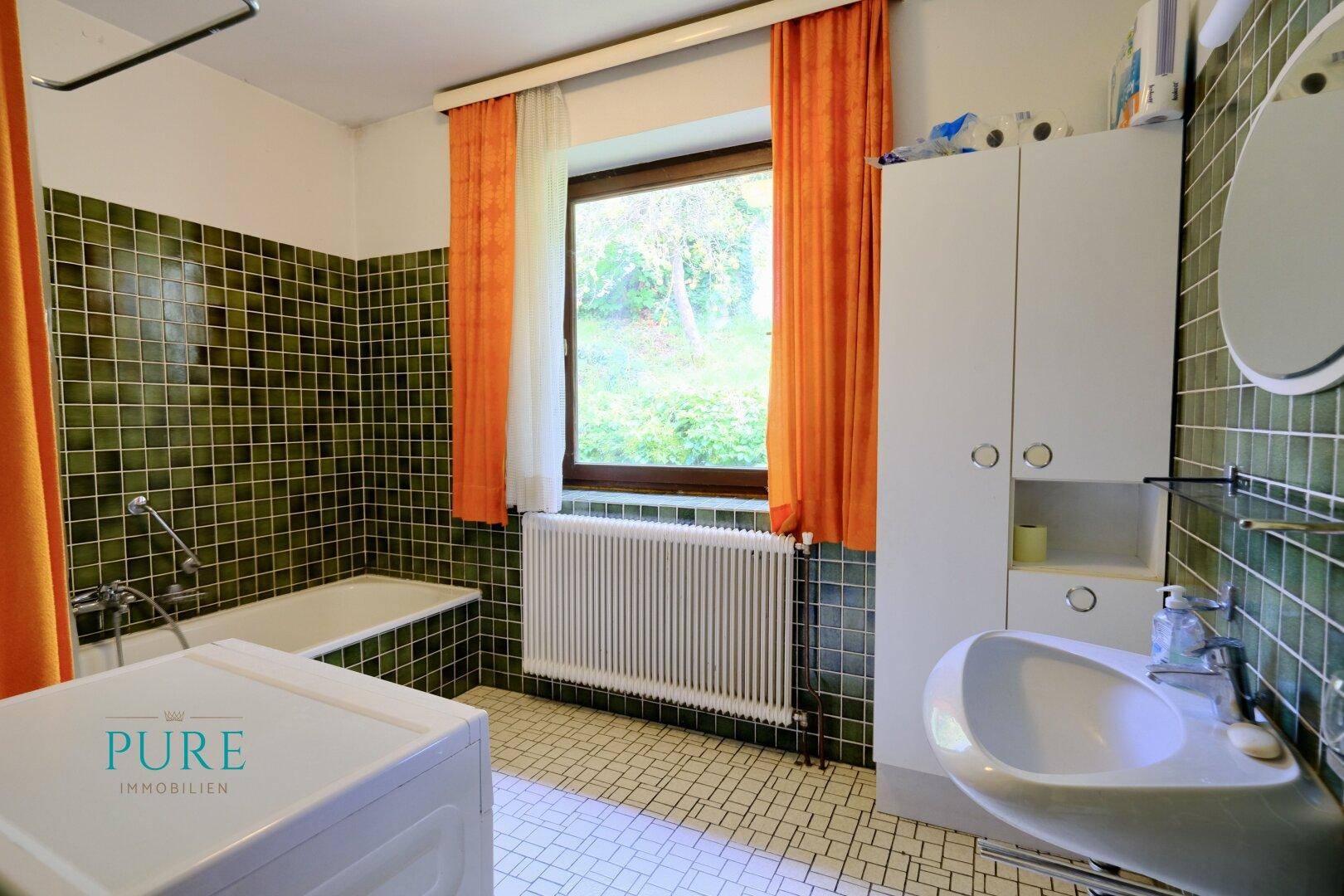 Badezimmer im Stil der 80er Jahre mit grünen Fliesen, Badewanne und Fenster.