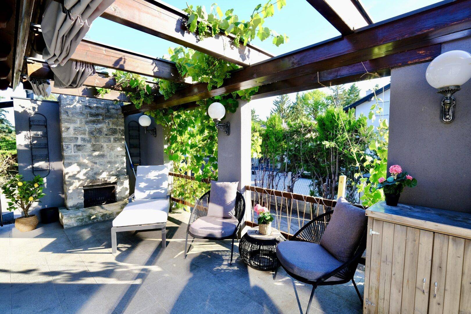 Gemütliche Terrasse mit Sitzgelegenheiten, Kamin und üppiger Bepflanzung für entspannte Stunden.