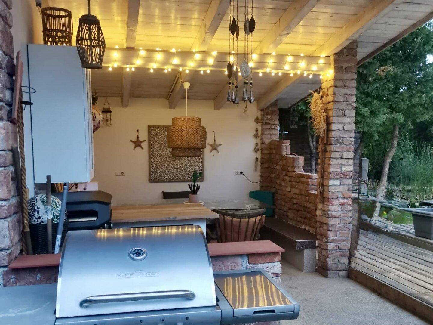 Beleuchteter Grillbereich im Freien mit moderner Ausstattung und gemütlicher Atmosphäre am Abend.