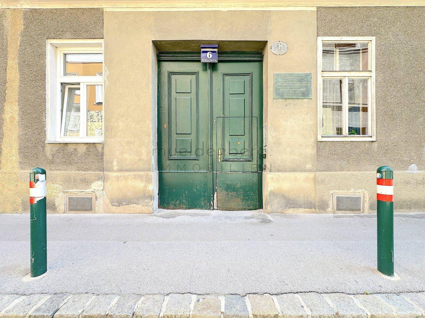 Detailansicht der grünen Doppeltür eines Altbaus mit Hausnummer und historischen Elementen.