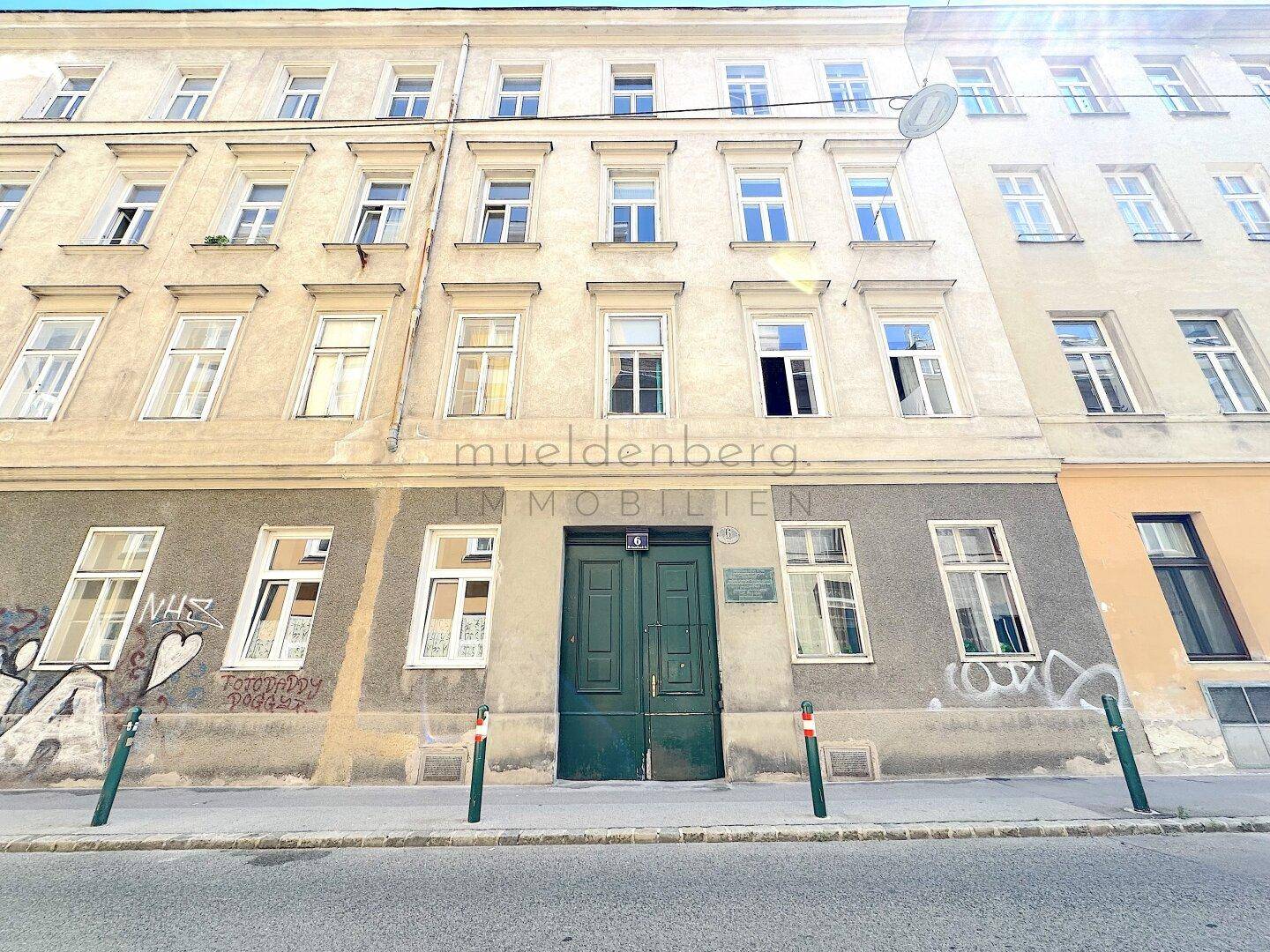 Fassade eines Altbaus mit grüner Eingangstür und Fenstern, die den Charme der Architektur widerspiegeln.