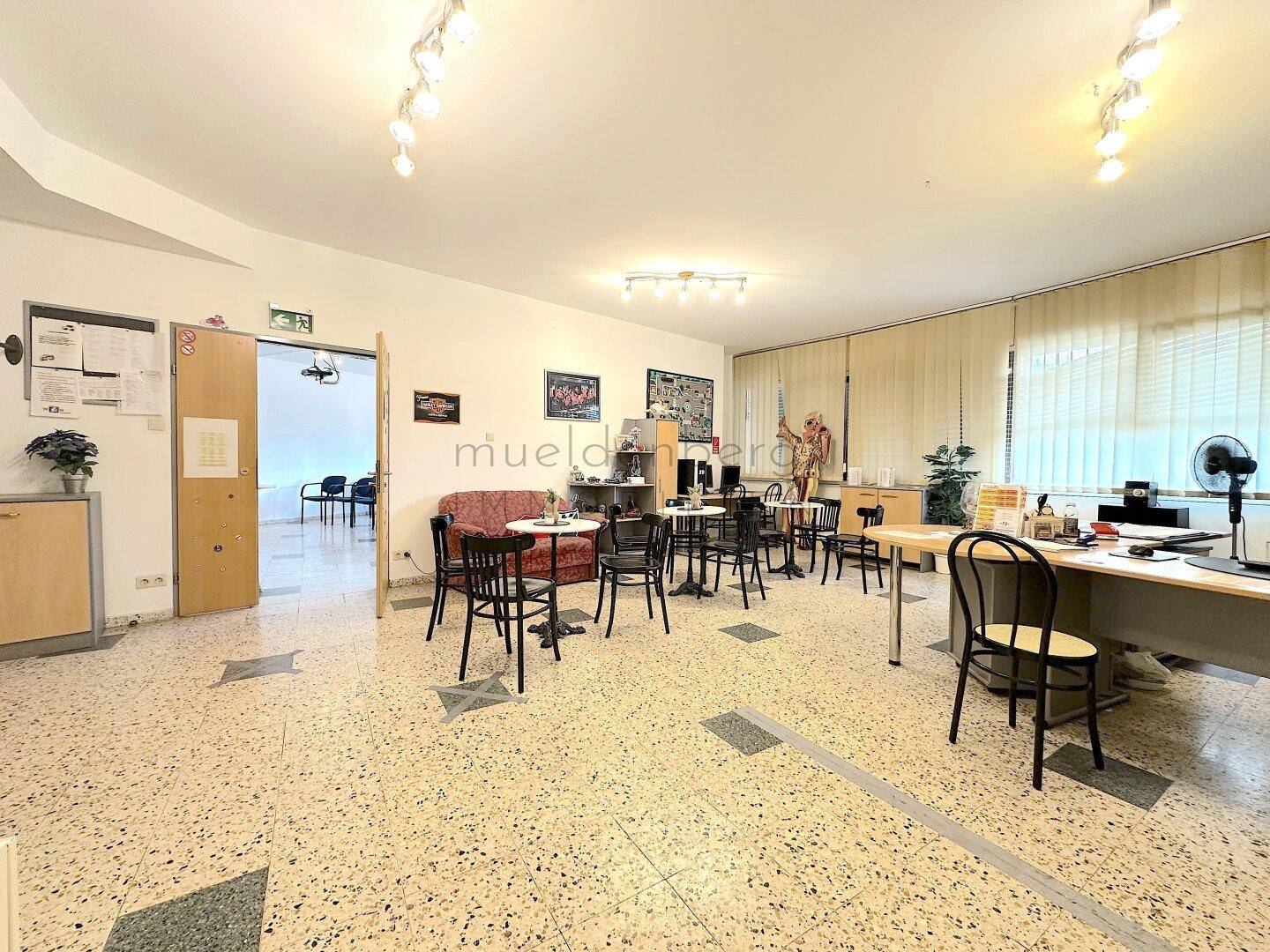 Offener Büroraum mit Sitzgelegenheiten, einem Sofa und mehreren Tischen, ideal für Besprechungen oder Pausen.