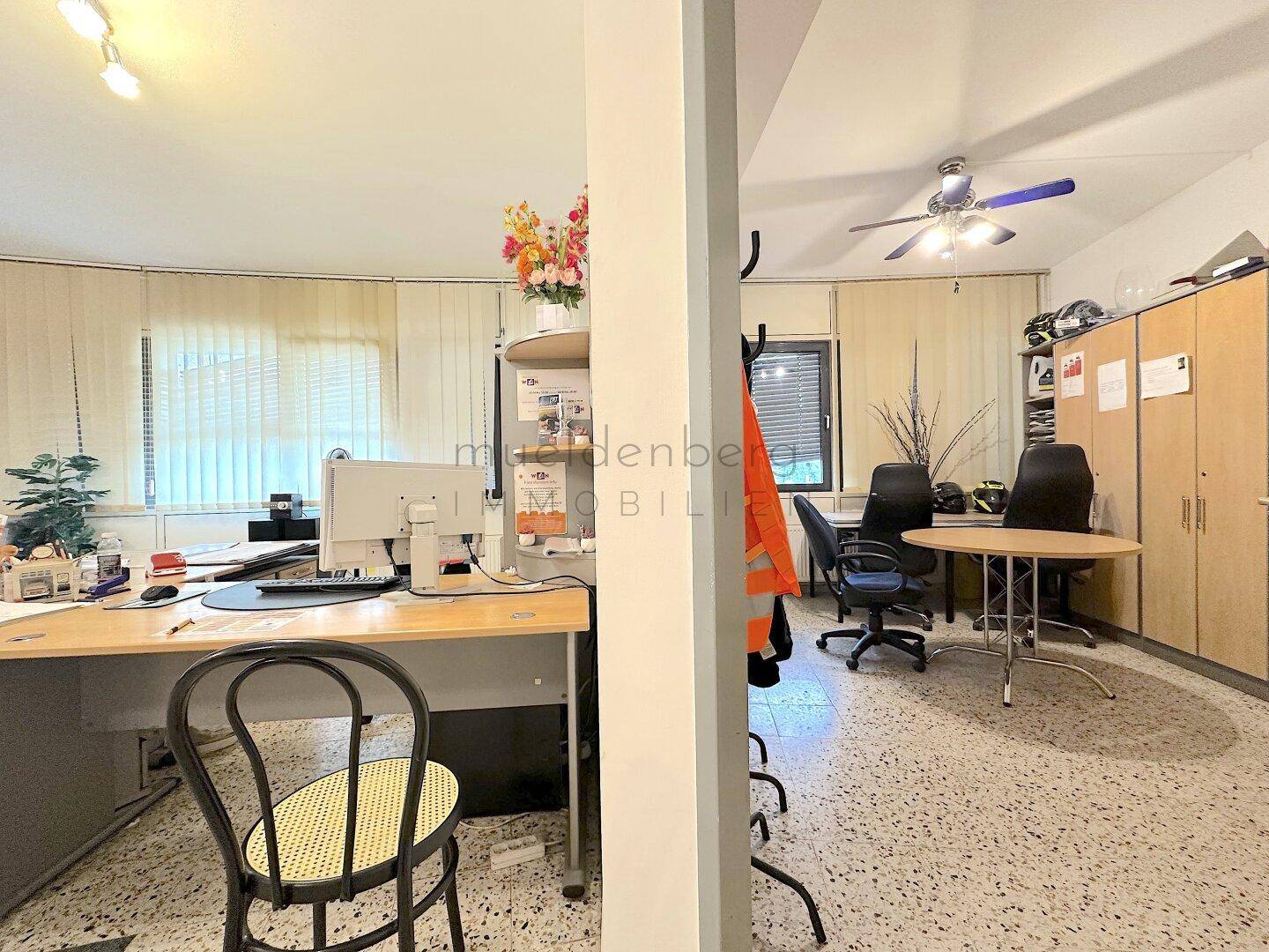 Büroarbeitsplatz mit einem Deckenventilator, Schränken und einem Schreibtisch, der eine funktionale Umgebung bietet.