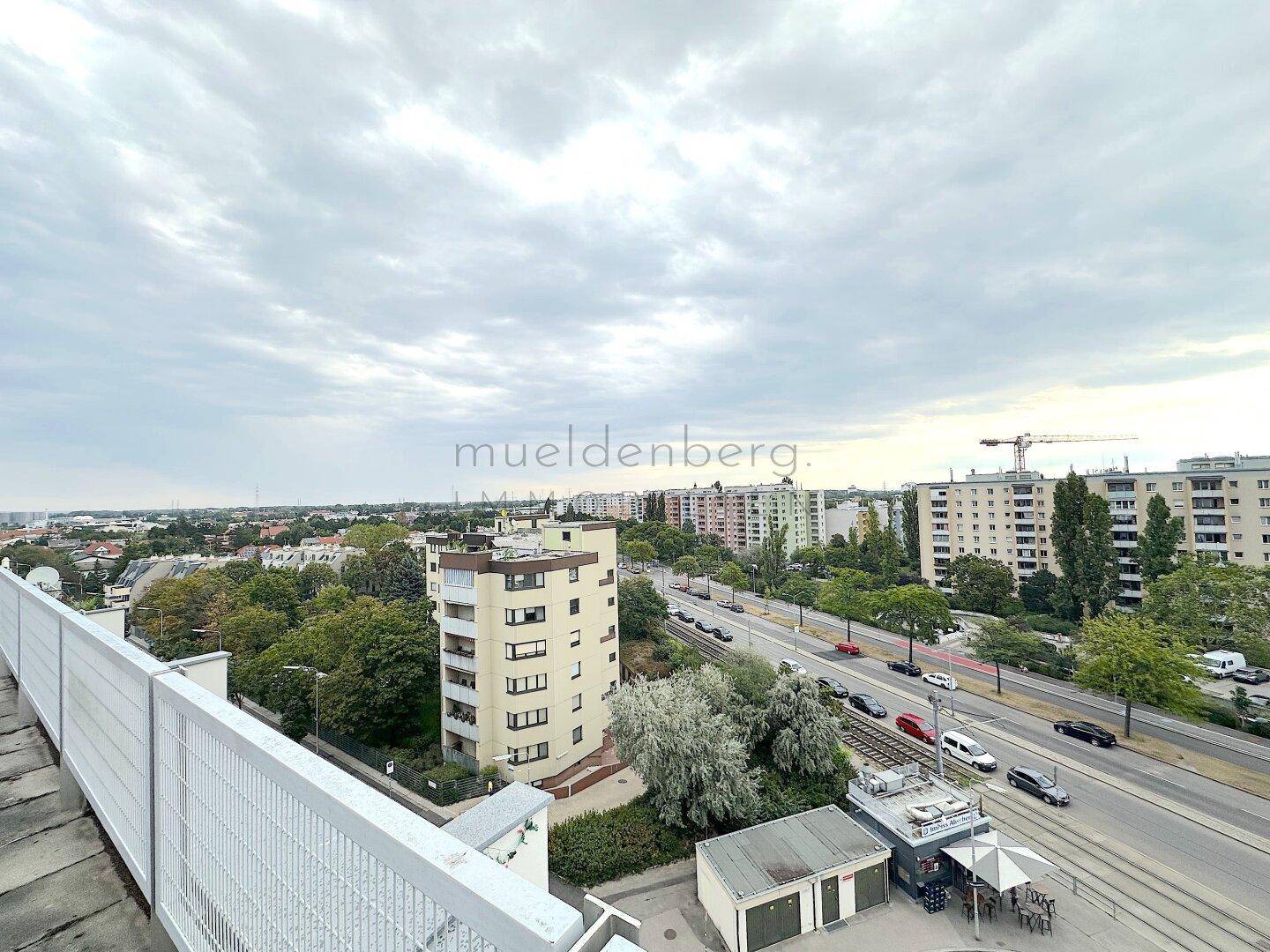 Panoramablick von der Dachterrasse auf die städtische Umgebung mit Gebäuden, Straßen und Straßenbahnschienen.