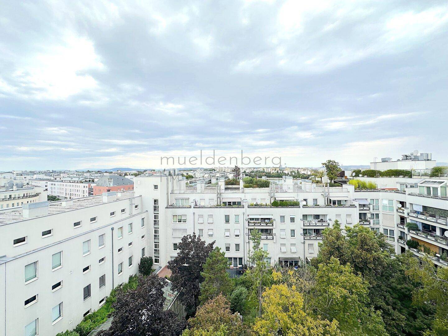 Panoramablick auf eine Wohnsiedlung mit vielen Gebäuden und üppigen Bäumen von einer erhöhten Position.