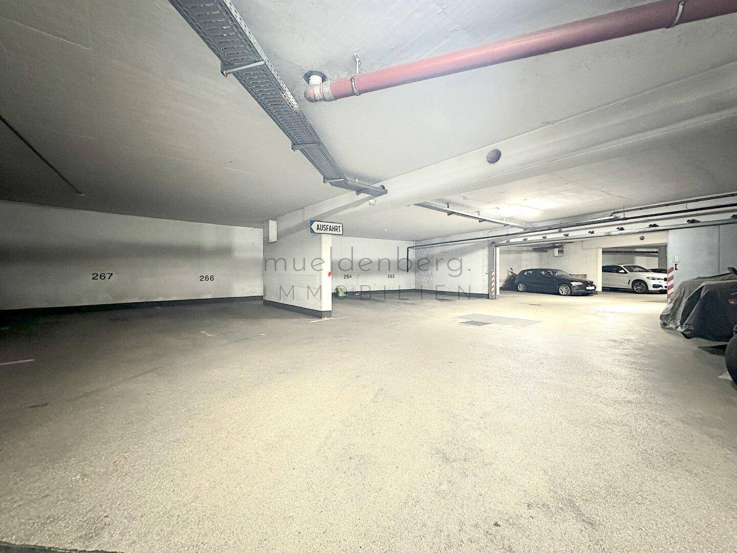Weiterer Bereich der Tiefgarage mit nummerierten Parkplätzen und abgestellten Fahrzeugen, gut organisiert.