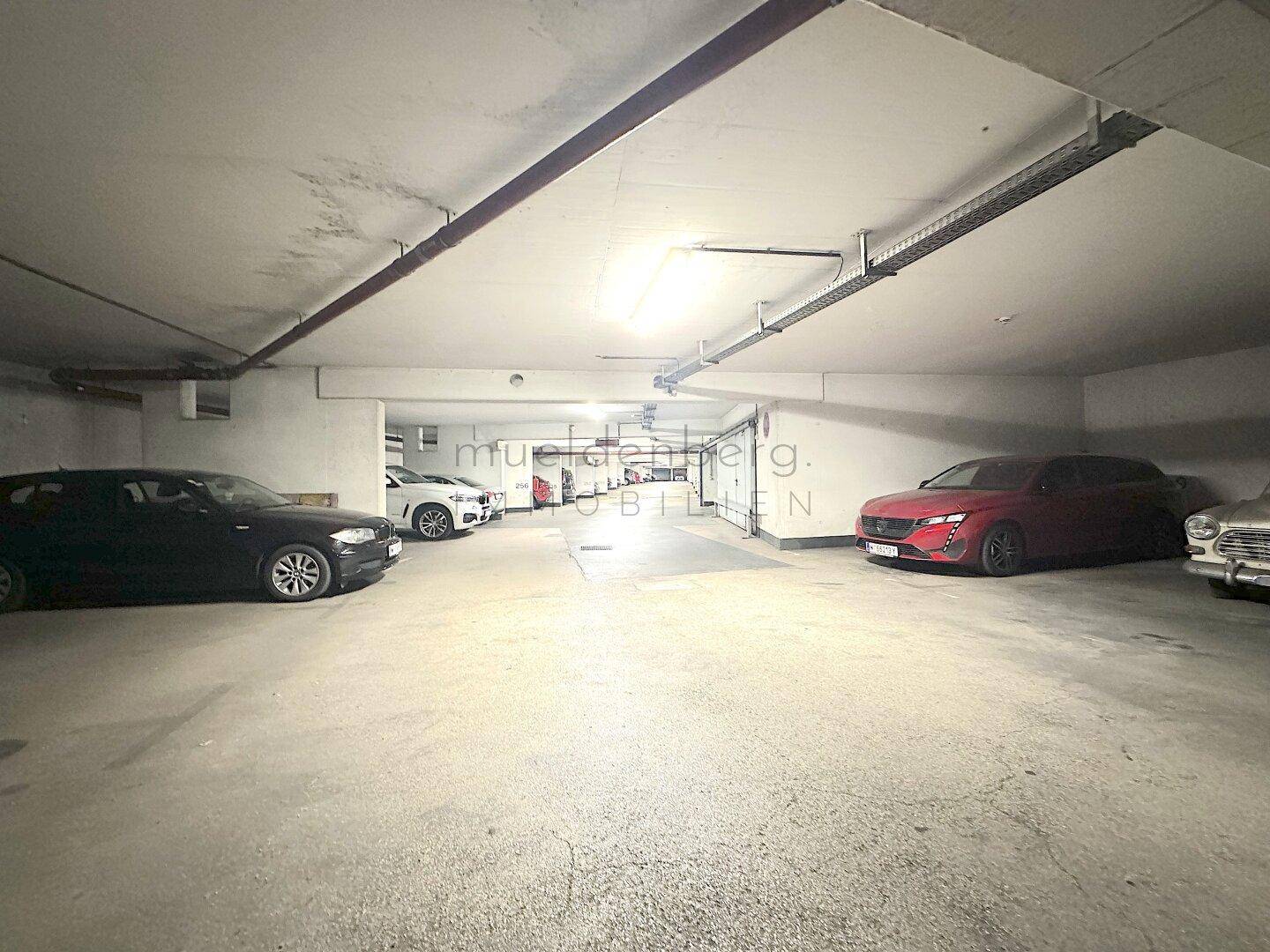 Innenansicht der Tiefgarage mit mehreren geparkten Autos und der robusten Betonkonstruktion.