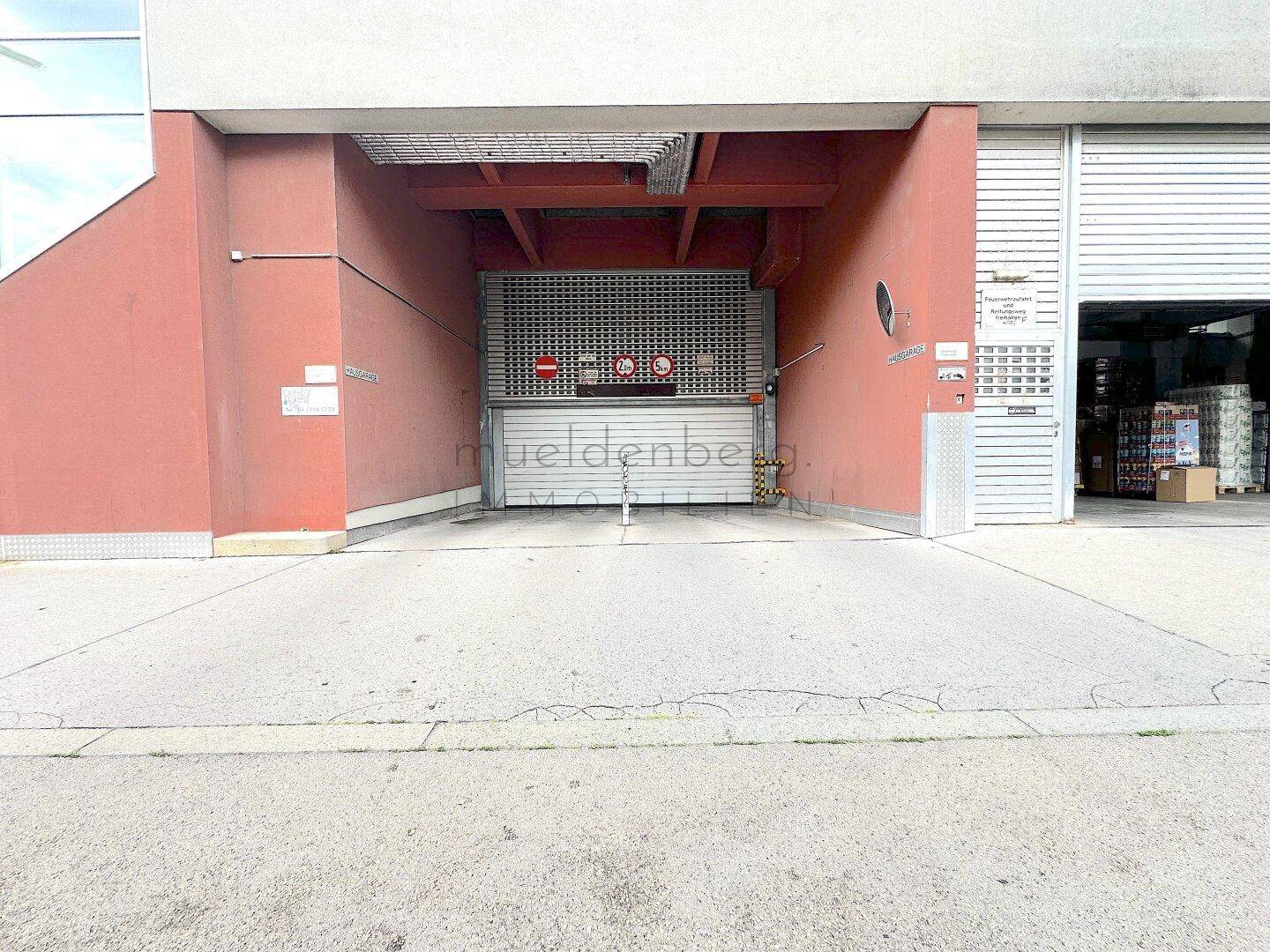 Eingang zu einer Tiefgarage mit einem Metalltor, das den Zugang zum Parkbereich ermöglicht.