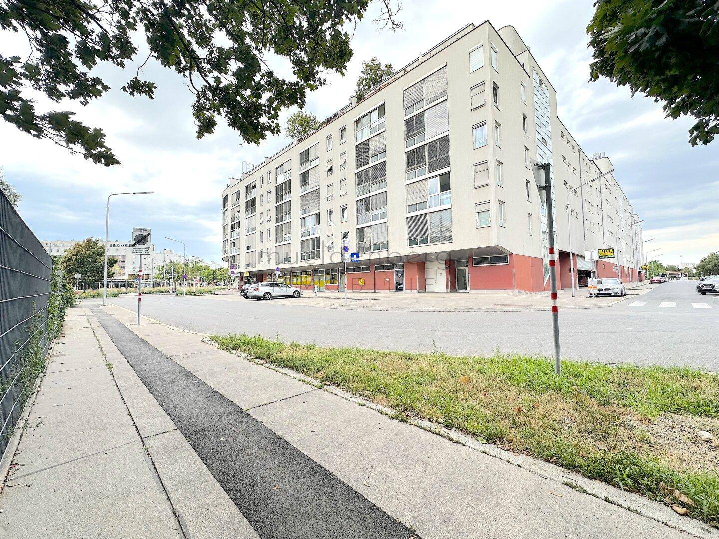 Weitwinkelansicht des gesamten Gebäudes von der Straße aus, mit Bürgersteig und Fahrbahn im Vordergrund.