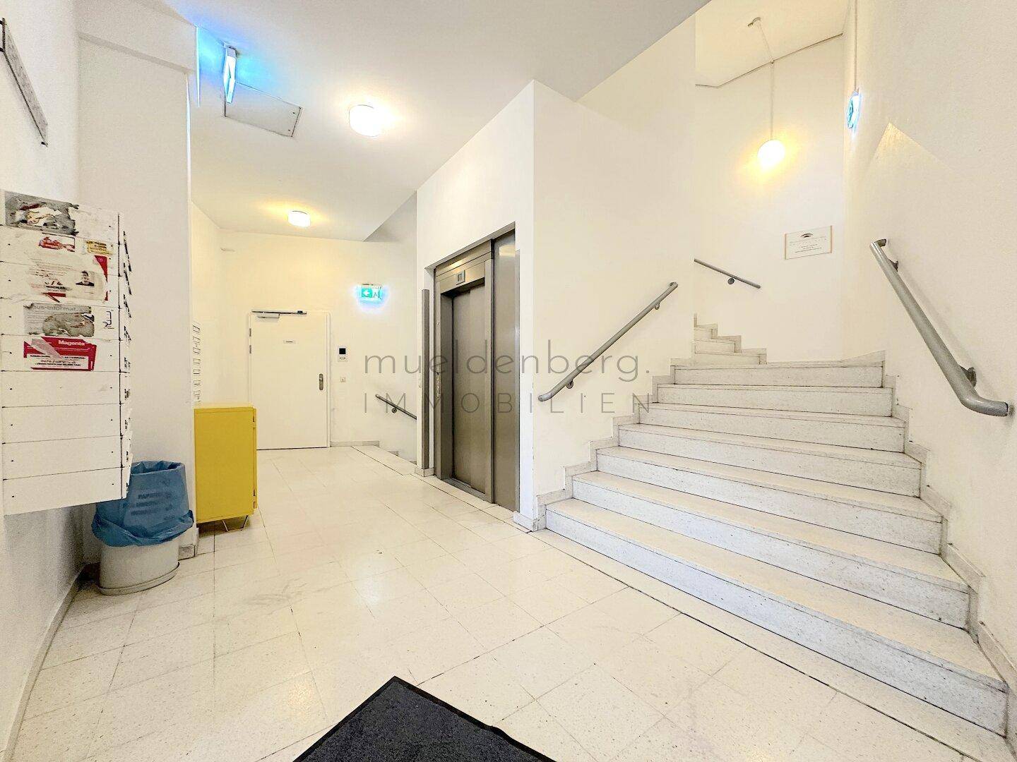 Geräumiges Treppenhaus mit breiter Marmortreppe, Aufzug und Briefkästen, gut beleuchtet und gepflegt.