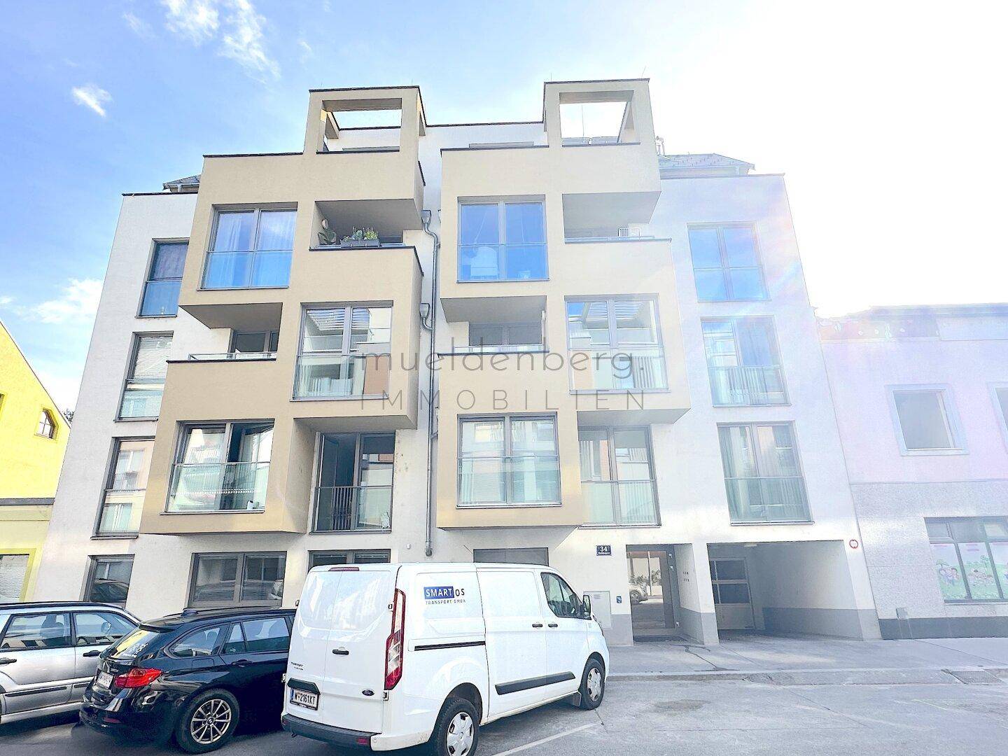 Moderne Wohnfassade mit großen Fenstern, Balkonen und zeitgenössischer Architektur.