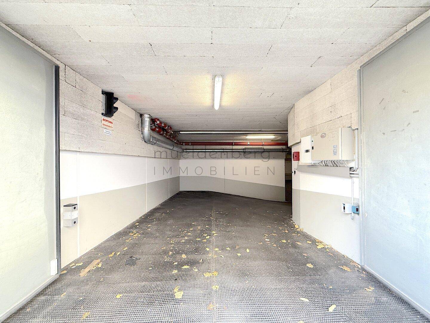 Innenansicht einer Tiefgarage mit Betonwänden und Beleuchtung.