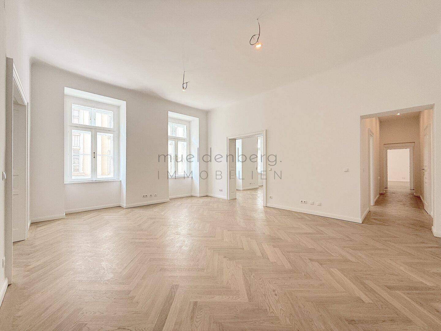 Weitläufiger, heller Raum mit Fischgrätparkett und hohen Decken, bereit zur individuellen Gestaltung.