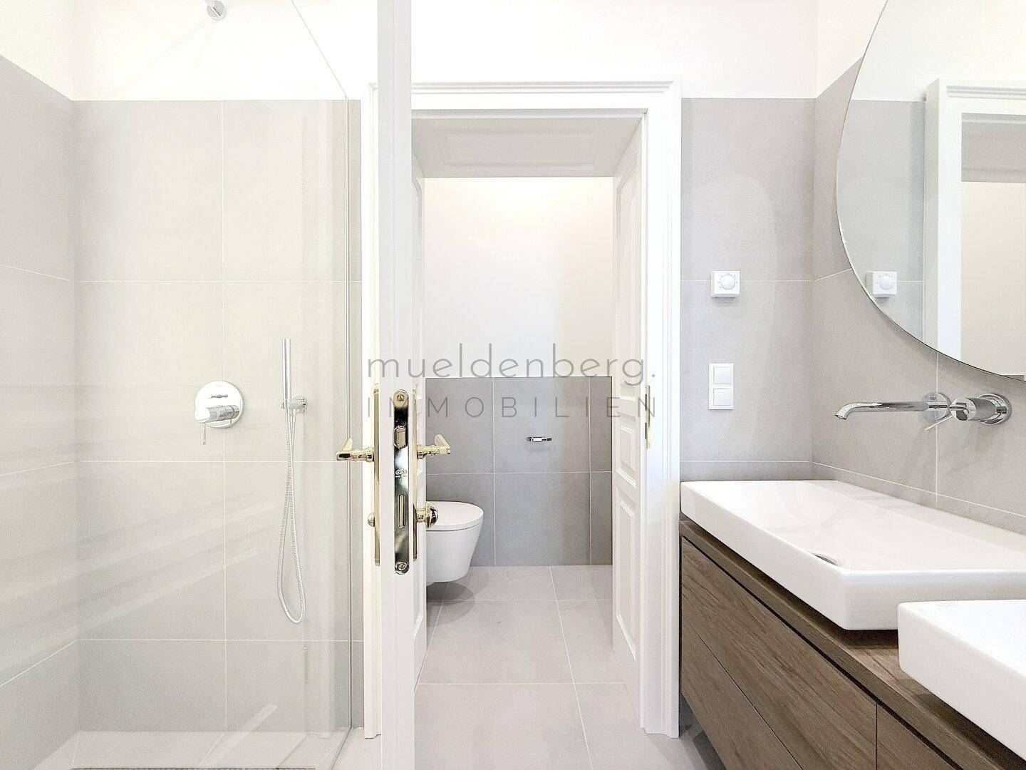 Modernes Badezimmer mit begehbarer Dusche und Blick auf die separate Toilette.