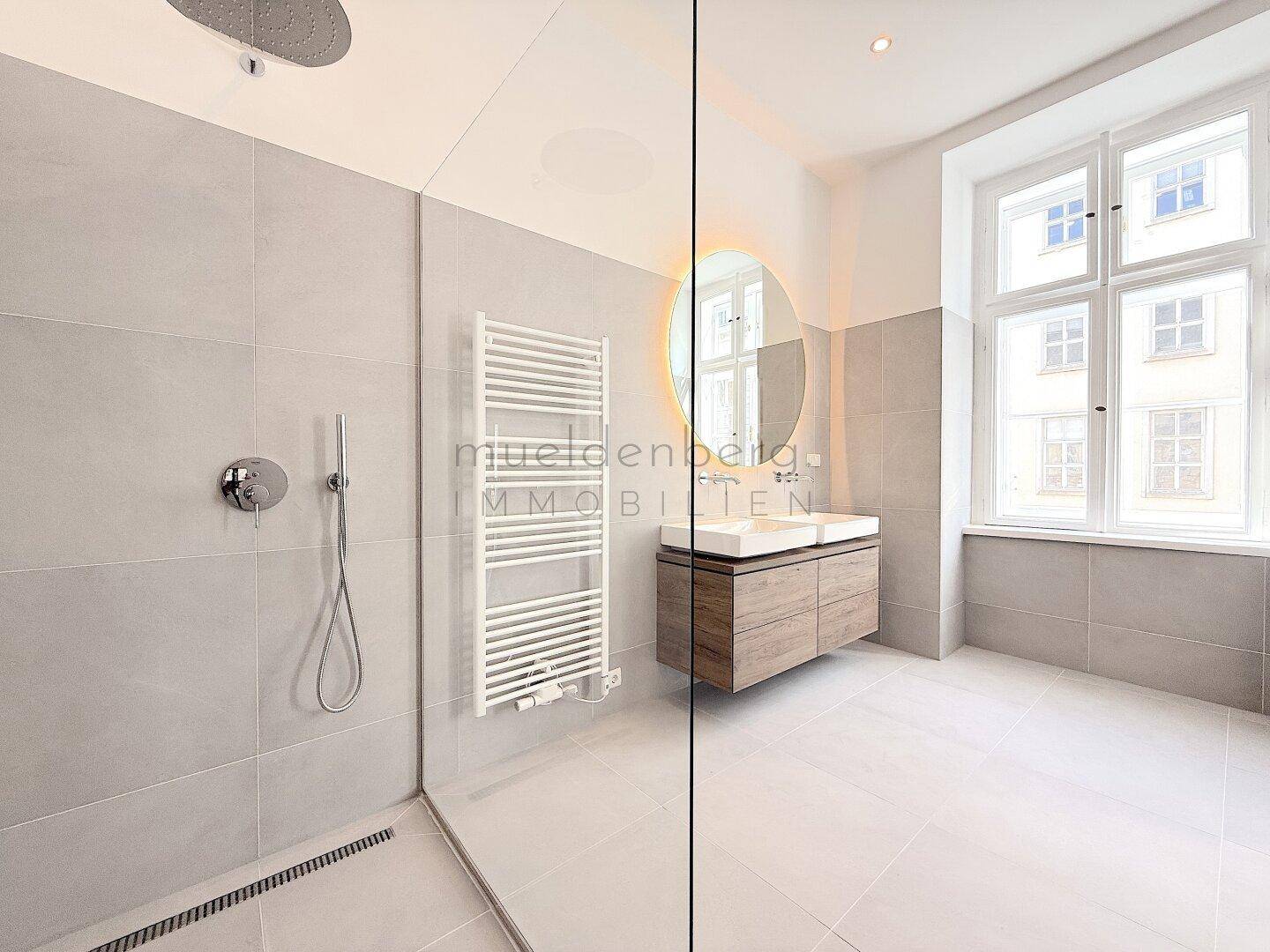 Helles, modernes Badezimmer mit begehbarer Dusche, Doppelwaschbecken und großem Fenster.