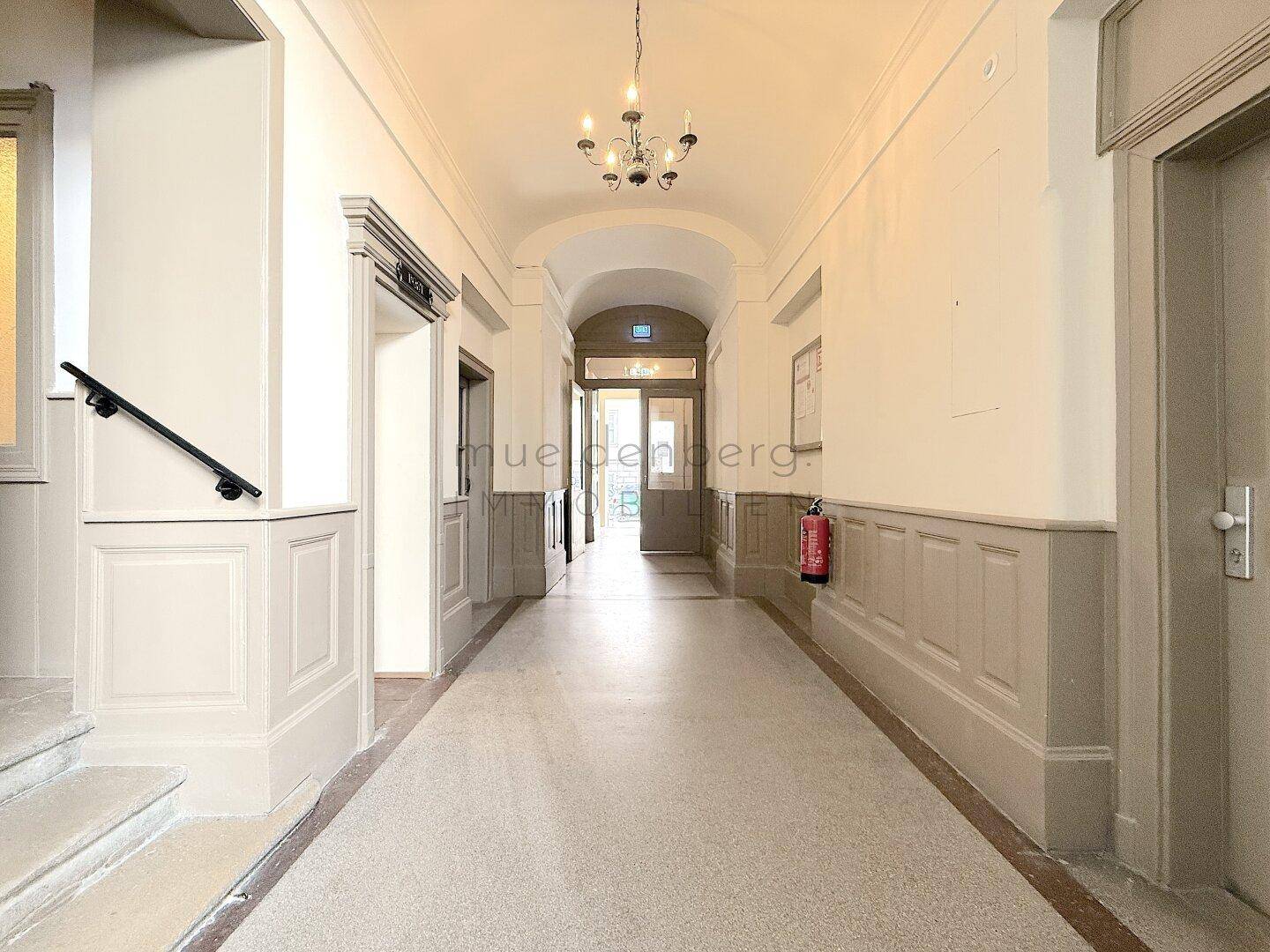 Langer Flur mit gewölbter Decke, Wandvertäfelungen und Kronleuchter, strahlt historischen Charme aus.