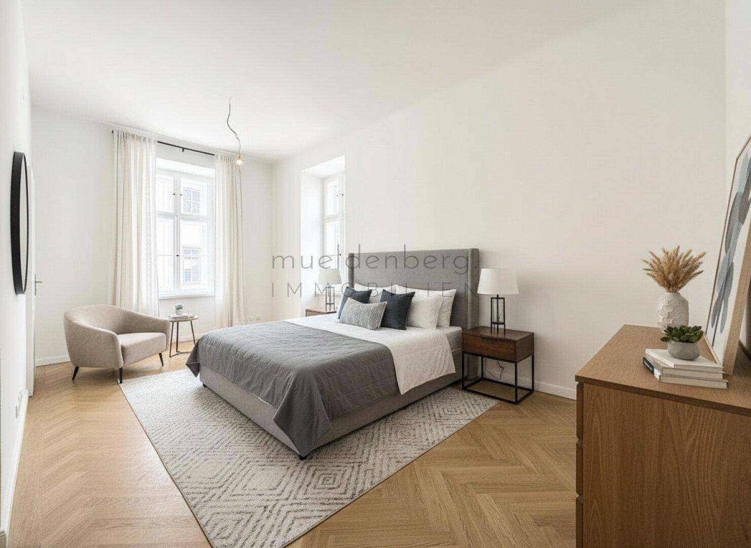 Modern eingerichtetes Schlafzimmer mit bequemem Bett, Fischgrätparkett und viel Tageslicht.
