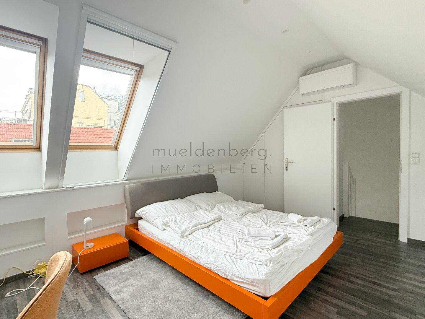 Gemütliches Schlafzimmer im Dachgeschoss mit zwei Dachfenstern und Klimaanlage.