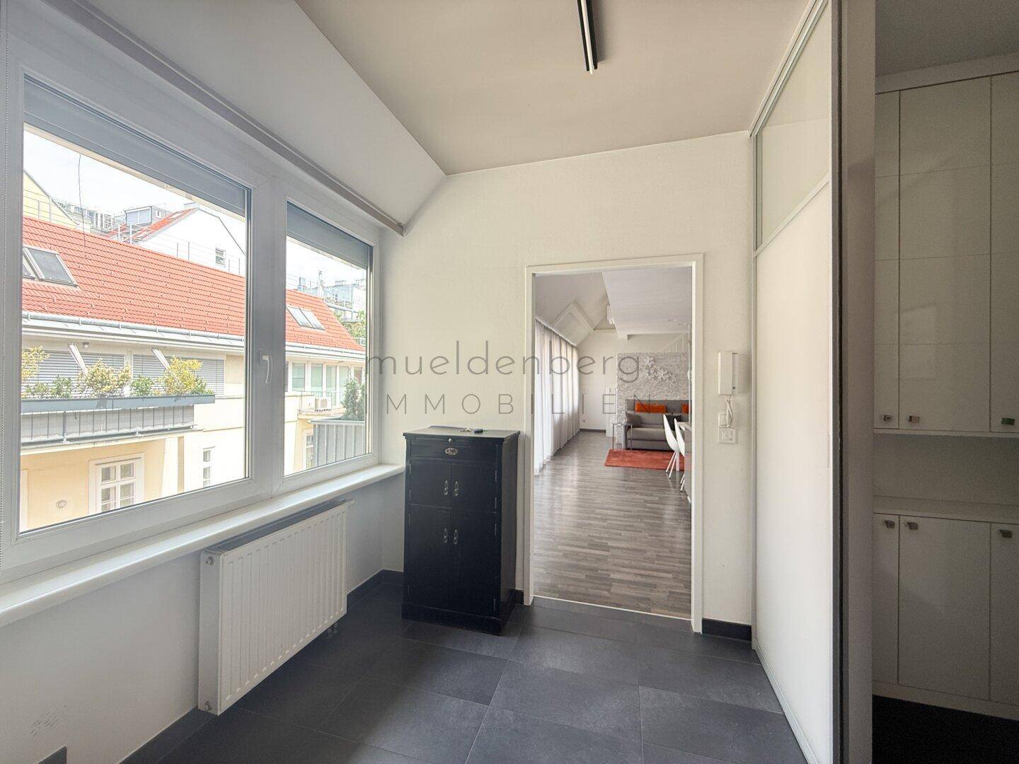 Heller Flur mit großen Fenstern, Heizkörper und Blick in den Wohnbereich.
